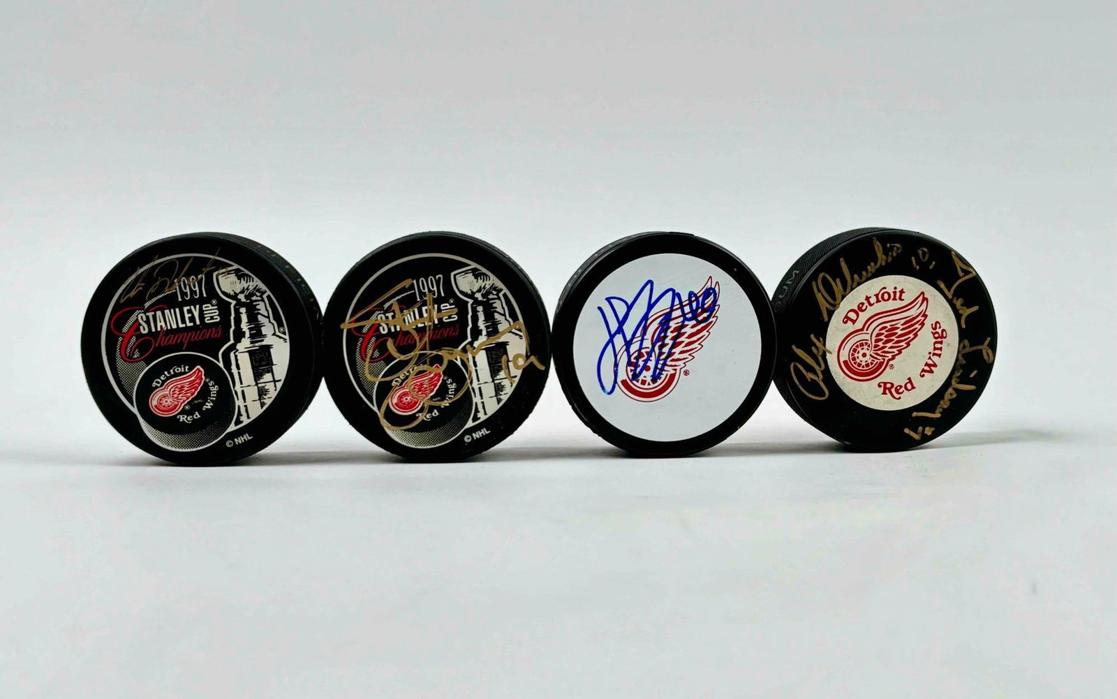 Four Signed NHL Detroit Red Wings Hockey Pucks: Four hockey pucks signed by various Detroit Red Wings players. Pucks are in good condition. Please see photos for additional details. Pucks include: One puck signed by Alex Delvacchio (#10) and Ted Li