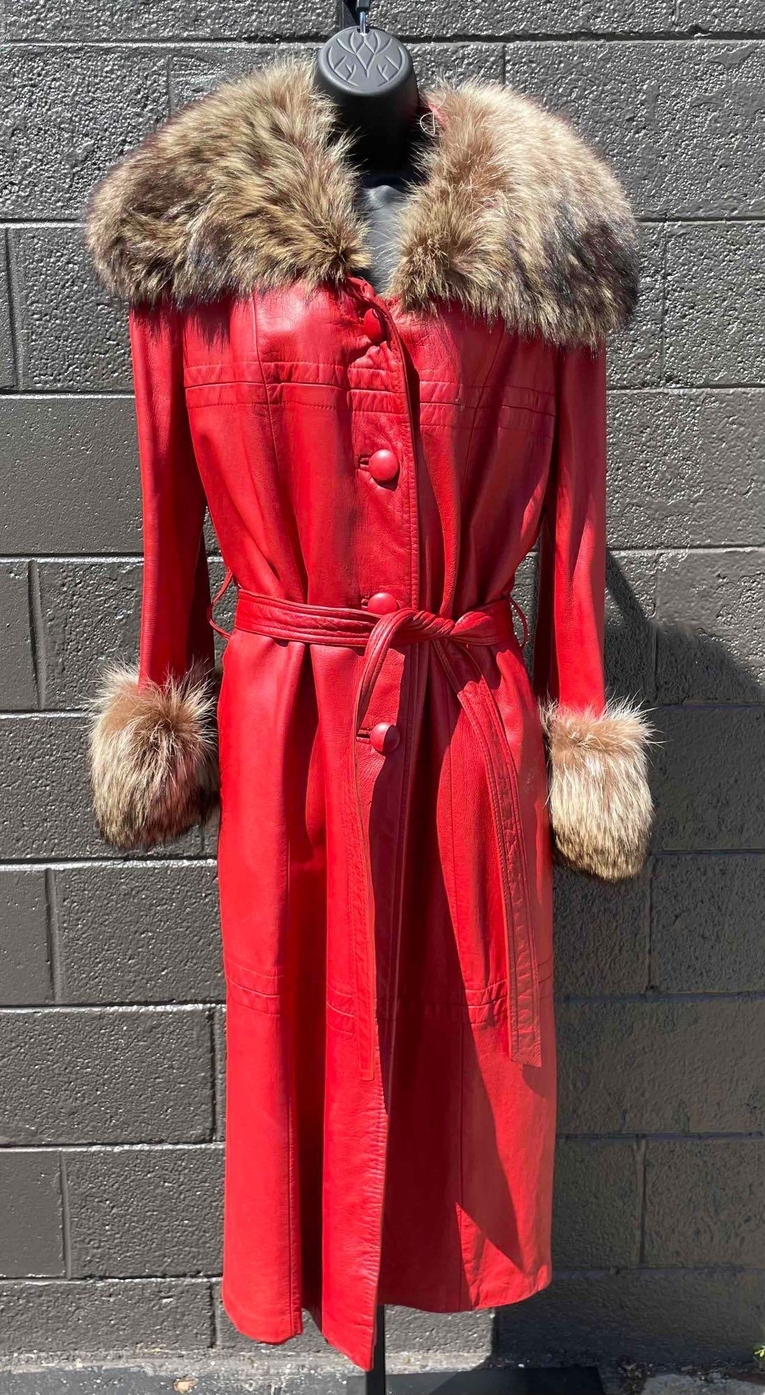 Red Leather Fur Trim Belted Trench Coat: Red leather belted trench coat with fur trimmed collar and cuffs. Coat has button closure. There are two tags labeled "Keira Leather Fashions" and "Townley Annis Furs." The Townley Annis Furs tag has 