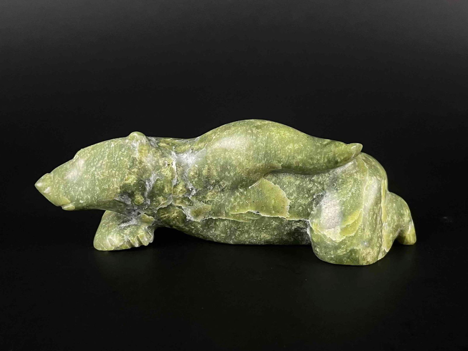 Carved Inuit Bear (Cape Dorset/Kinngait, 1970s): Inuit stone carving of a lounging bear. Piece is signed in Inuktitut syllabics on the foot. This piece was purchased on Cape Dorset/Kinngait, directly from the artist by collector Jon Jacobs, a promin