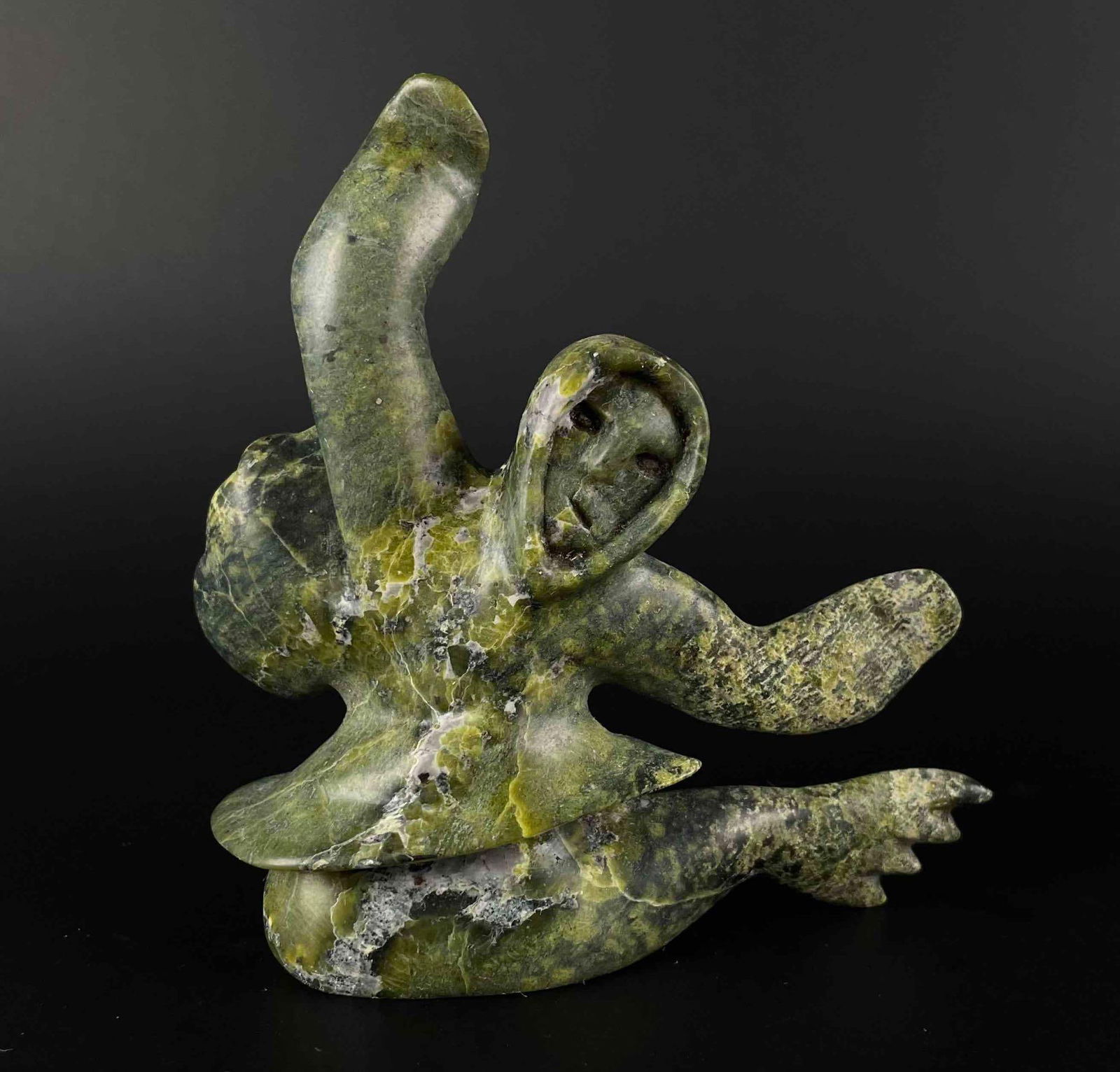 Inuit Carving in Green Serpentine (Tytoosie Tunnillie, Cape Dorset/Kinngait): Inuit serpentine figural carving. Polished green serpentine. Piece is signed in Inuktitut syllabics on the foot. Signed Tyootsie Tunnille. This piece was purchased in Kinngait/Cape Dorset, directly fr