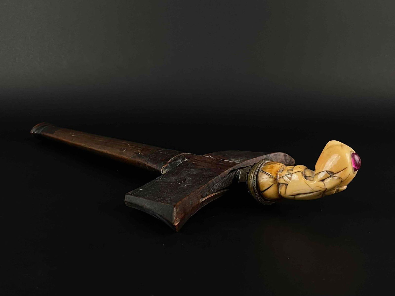 Indonesian Kris Dagger with Bone and Ruby Hilt: Indonesian kris or keris dagger with ruby encrusted hilt. Blade is meteorite. Hilt exhibits abstract hooded figure with a forward lean and cabochon ruby crown. Sheath is deep toned wood. From the priv