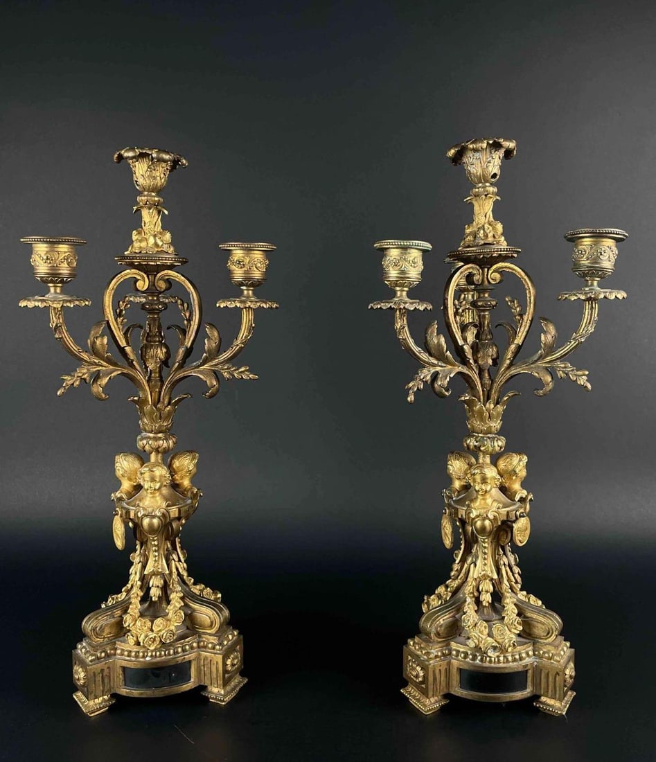 Pair of Antique Rococo Brass Candleabras: Pair of brass candlestick holders in Rococo design. Candlestick holders have ornate floral detail and cameo features. Both are in good condition with areas of patina. Please see photos for additional