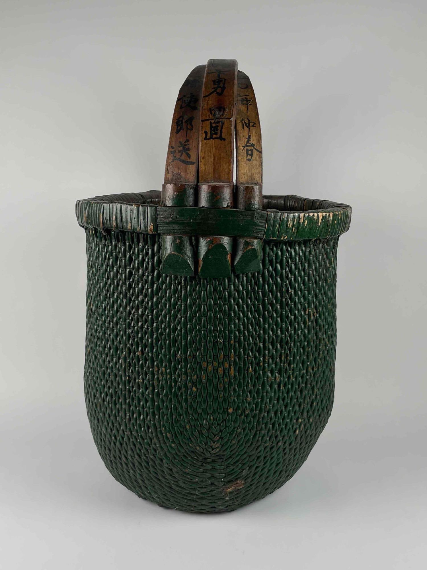 Green Antique Chinese Rice Basket with Bent Bamboo Handle (C. Early 20th Century): Antique green Chinese woven rice gathering basket with bent bamboo handles. Circa early 20th century. Chinese characters are present on each side of handle. Basket is in excellent antique condition wi