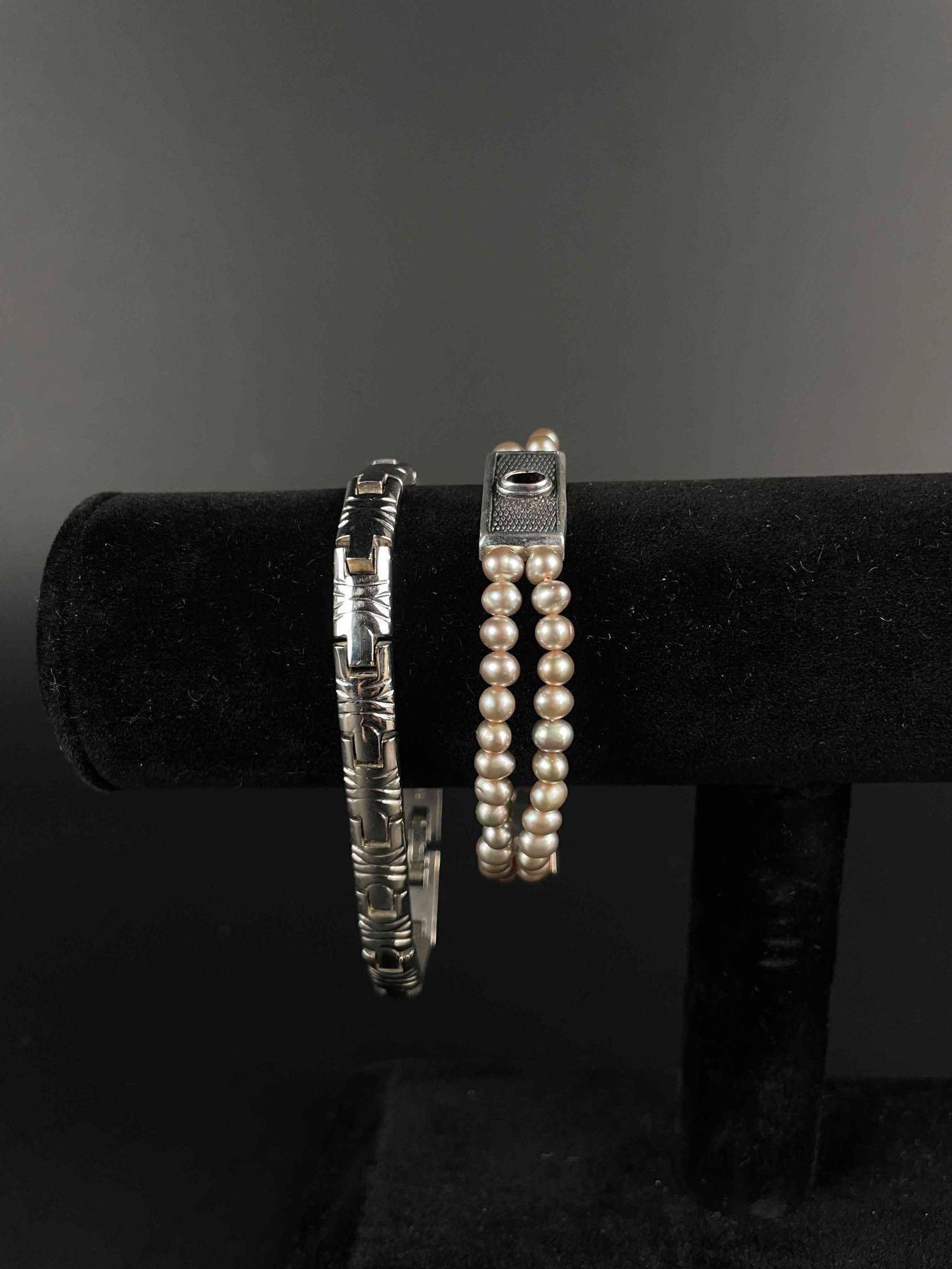 Pair of Sterling Silver Bracelets: Pair of sterling silver bracelets. Sterling silver etched ornate link bracelet with tab lock. 925 hallmark is located on inner band. Double stranded freshwater pearl bracelet with sterling silver gems