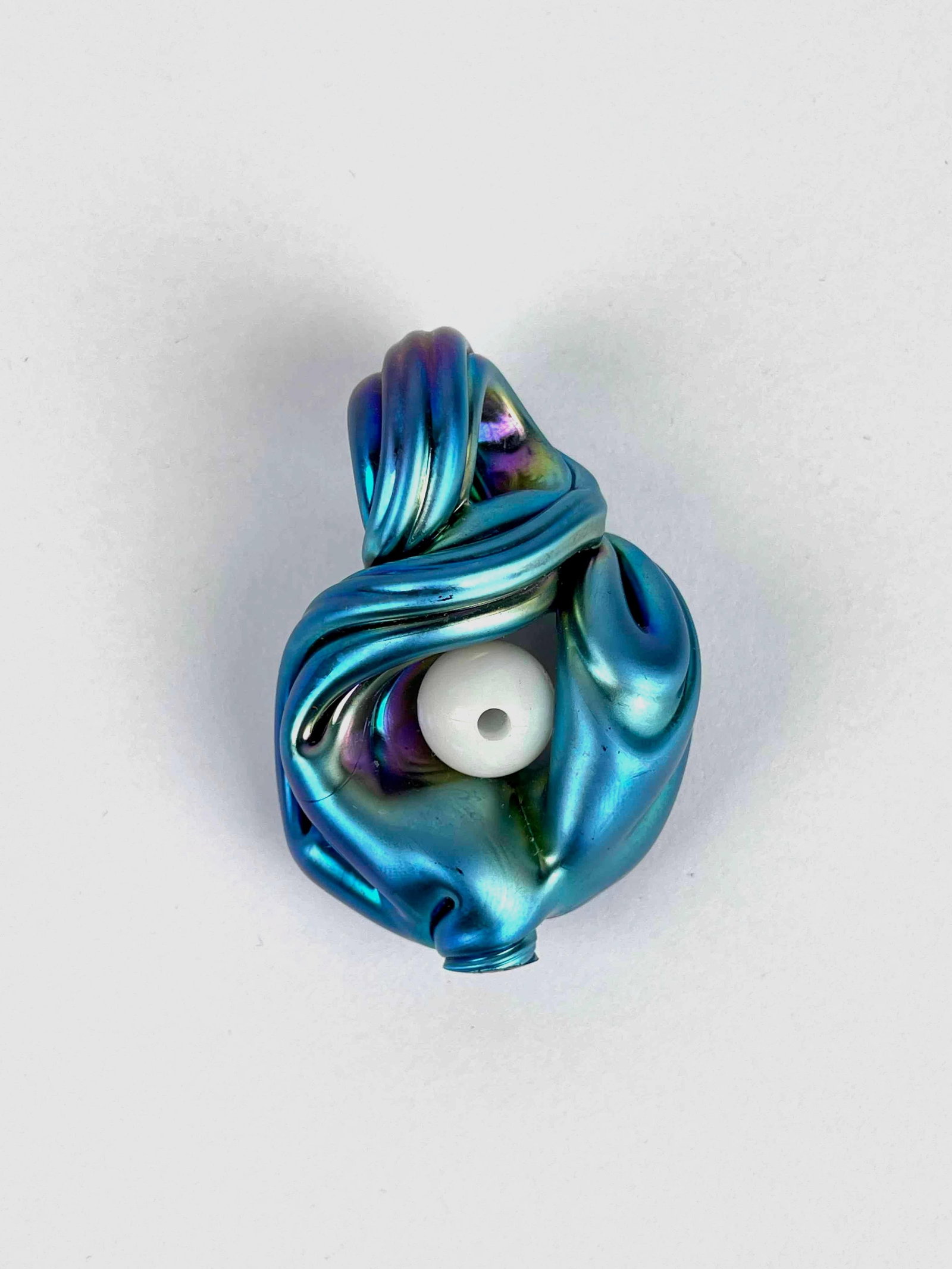 Charles Lotton Irridescent Glass Knot Pendant: Iridescent glass knot pendant by Charles Lotton. Colors range from blues, purples, and greens with a pierced white bead in center. Artist signature is engraved in lower region. In good condition. Plea