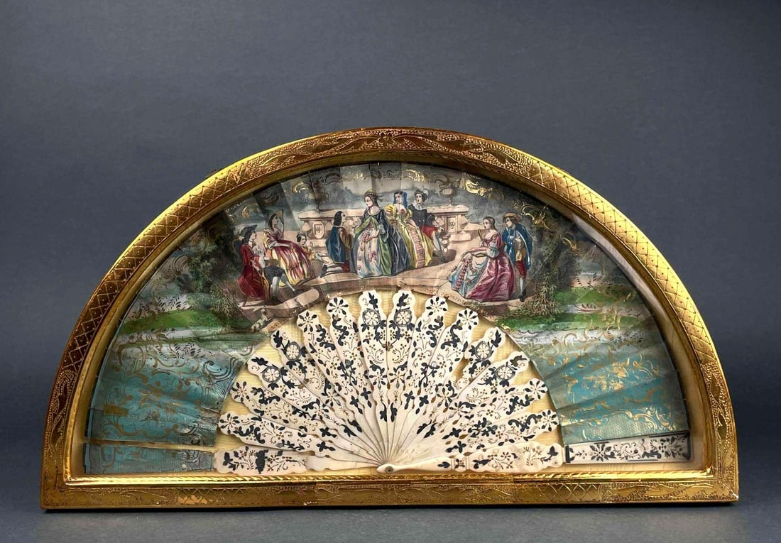Antique Bone and Paper Fan in Gesso Shadow Box: Antique frame in gilted shadow box frame. There is a colorful figural scene across fan, and hand painted detailing on pivot pin. Shadow box frame has two clasps on top to open the front window. Fan is