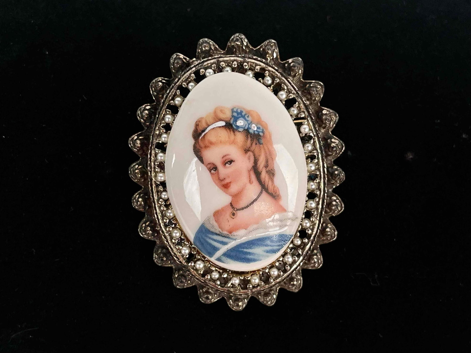 Limoges France Porcelain Female Portrait Oval Brooch: Female portrait in oval shaped brooch and floral setting by Limoges France. Brooch has seed pearl detail. Limoge France hallmark is present on back of brooch. In excellent condition. Please see photos