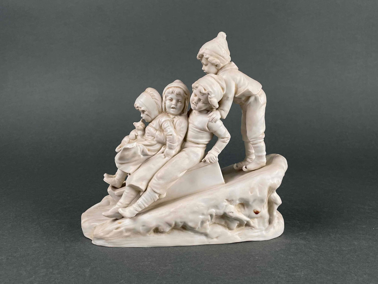 Bisque Sculpture of Children Sledding: Bisque sculpture of children sledding. Identification number 12 present on bottom. In good condition with signs of wear such as light discoloration. Please see photos for additional details. Dimension