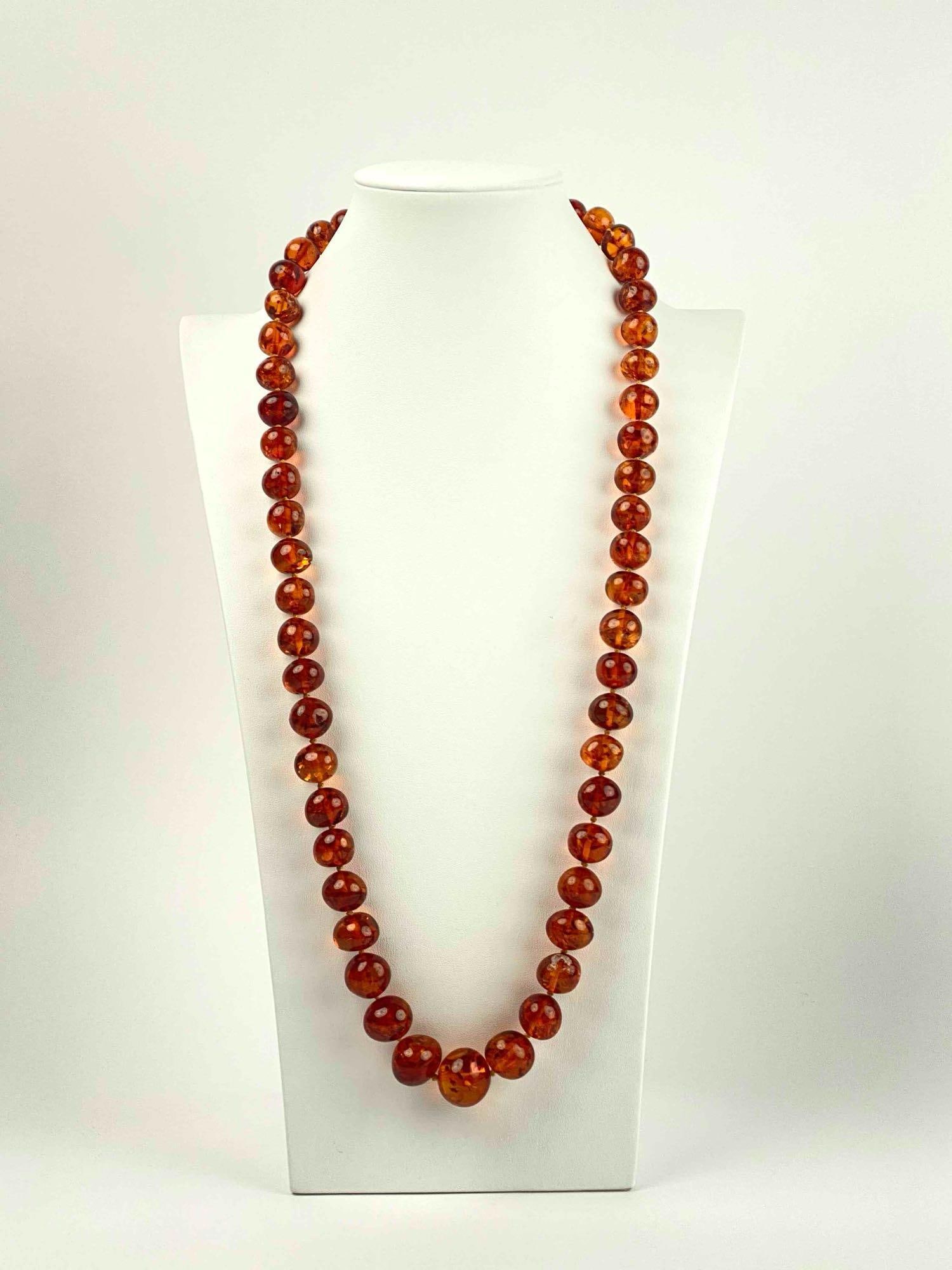 Beaded Amber Necklace: Beaded necklace with amber beads. Beads are larger as they meet the center. Necklace has a screw back clasp. In excellent condition. Please see photos for additional details. Length: 33" Weight: 106.5