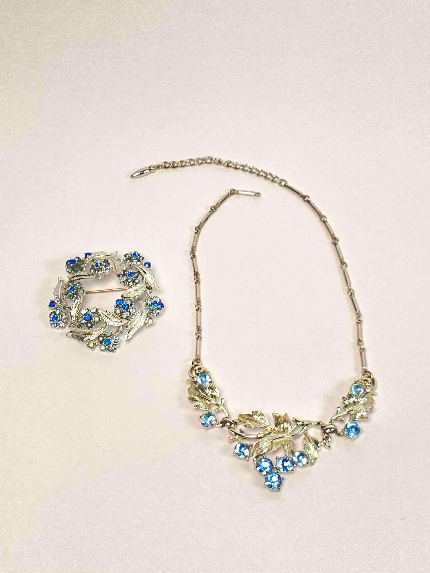 Coro Rhinestone Bracelet and Brooch: Rhinestone bracelet and brooch set by Coro. Jewelry is silver toned with round cut blue rhinestones and foliate design. Coro hallmark is present on back of both pieces. In excellent condition. Please