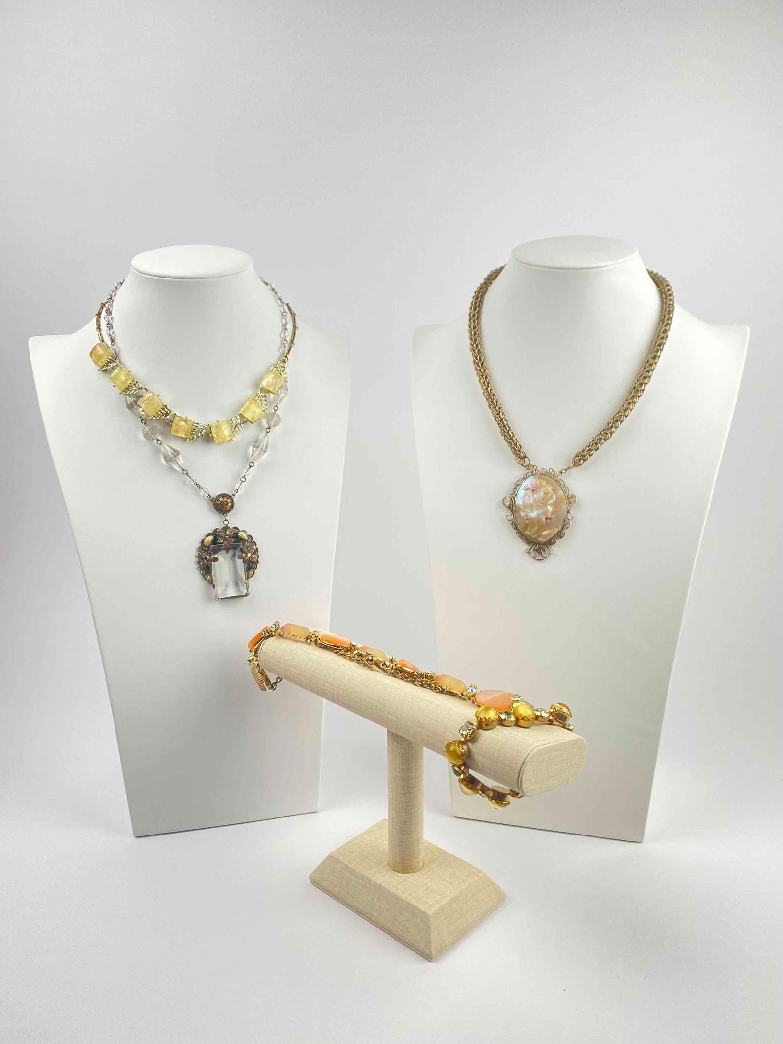 Group of Art Noveau Jewelry: Group of art nouveau jewelry including four necklaces and a bracelet. Includes one Mother of Pearl cameo necklace, one rhinestone and faux pearl necklace, two lucite necklaces, and one glass and rhine