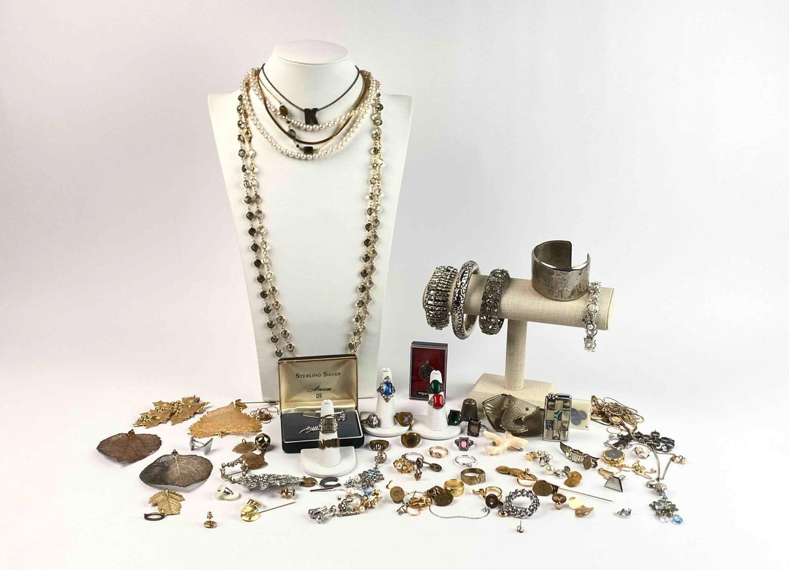 Collection of Costume Jewelry: A large collection of costume jewelry. Includes necklaces, rings, pins, brooches, and bracelets. Also includes a Mother of Pearl lighter. Includes a sterling silver Anson tie clip. Many "K" monogramme