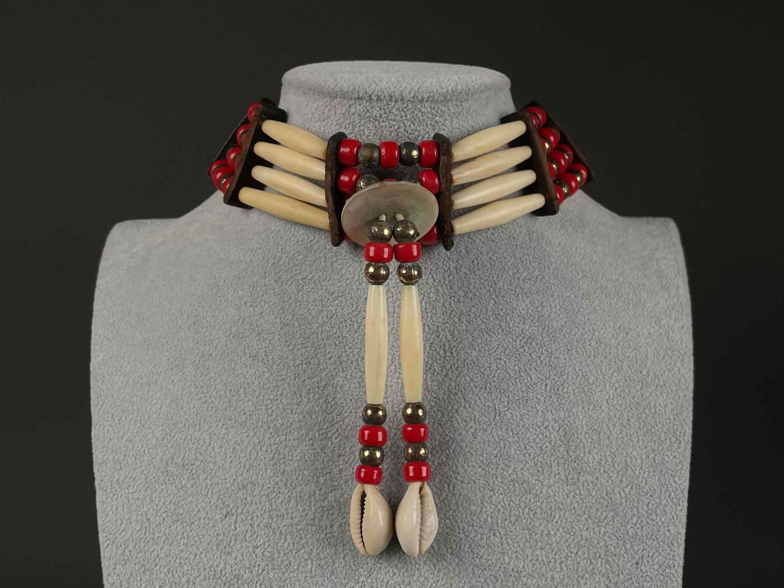 Native American Bone Pipe Choker: Traditional Native American choker crafted from white bone hair pipes, red and gold toned beads, and leather ties. The choker is composed of three parallel rows of short, tubular bone hair pipes space