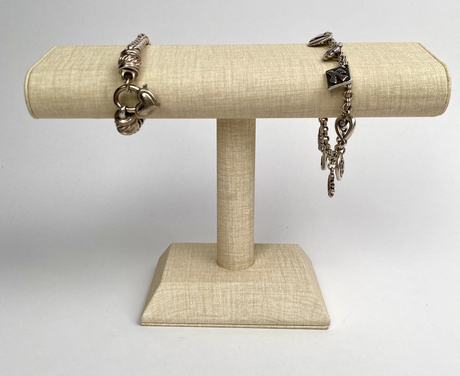 Two Sterling Silver Charm Bracelets: A pair of sterling silver charm bracelets. The first bracelet is adorned with multiple charms, including hearts and floral motifs, attached to a chain link design. The second bracelet features a braid