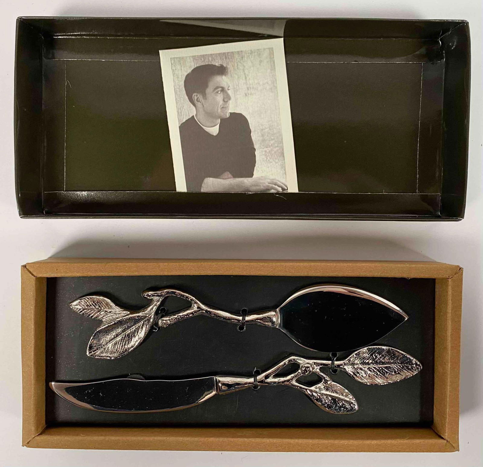 Michael Aram Sleepy Hollow Cheese Knife Set in Box: Michael Aram Sleepy Hollow Cheese Knife Set. The set includes two knives crafted from high-quality stainless steel with an artistic branch and leaf design. Made in India, the knives are presented in t