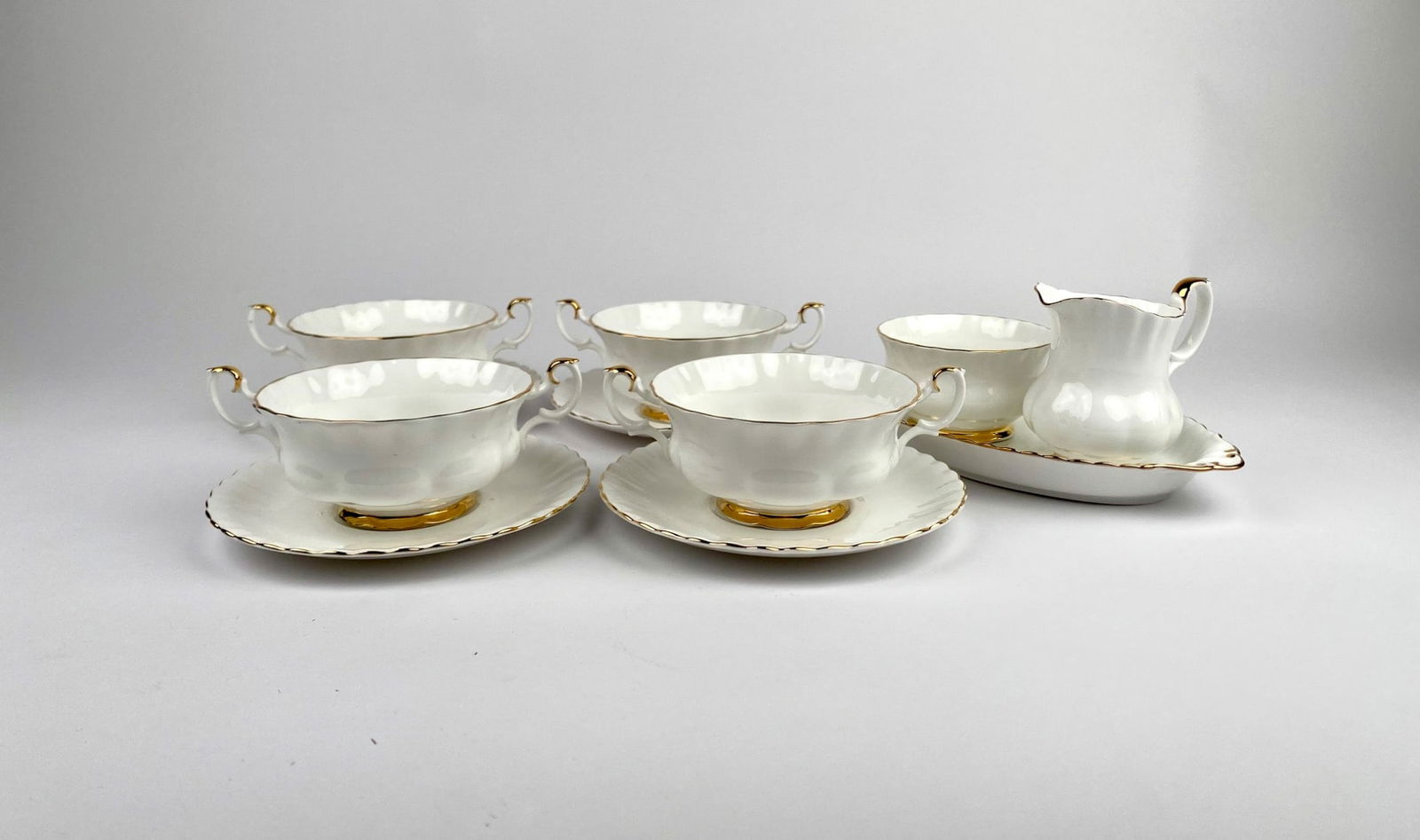 Royal Albert Val D’or Bone China Soup Bowls Set with Creamer and Sugar: Royal Albert Val D’or Bone China made in England featuring four two-handled soup bowls with matching saucers, and a creamer and sugar bowl on a tray. Each piece is accented with gold trim, creating