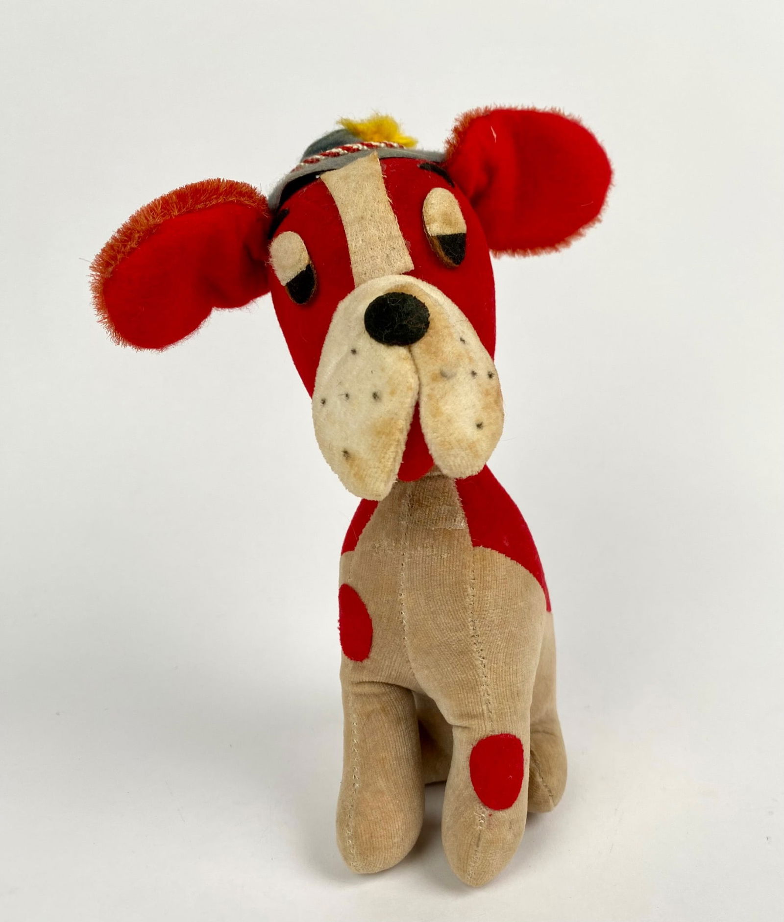 Vintage R. Dakin and Co Dream Pets Red Plush Dog: Dream Pets velvet plush dog featuring red and tan coloring, spots, and stitched details. The dog wears a Bavarian-style felt hat with rope trim and yellow pom-pom detail. A cloth tag reads â̈́