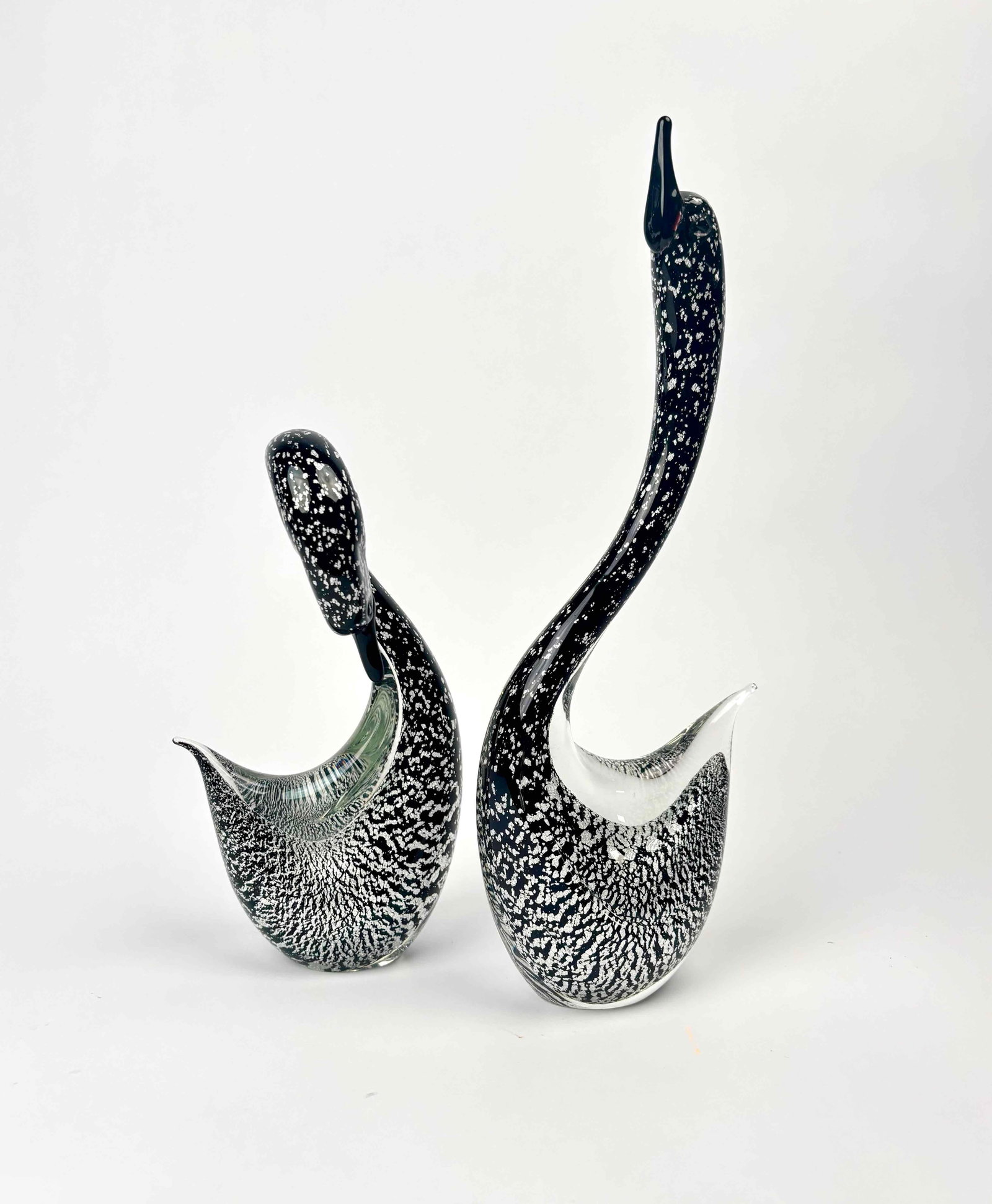Pair of Murano Glass Swans (Italy): Two black and white Murano swans with silver tone embellishment. Black and white mottled sculpture. Smooth and polished base. Excellent condition. Please see photos for additional details. Dimensions: