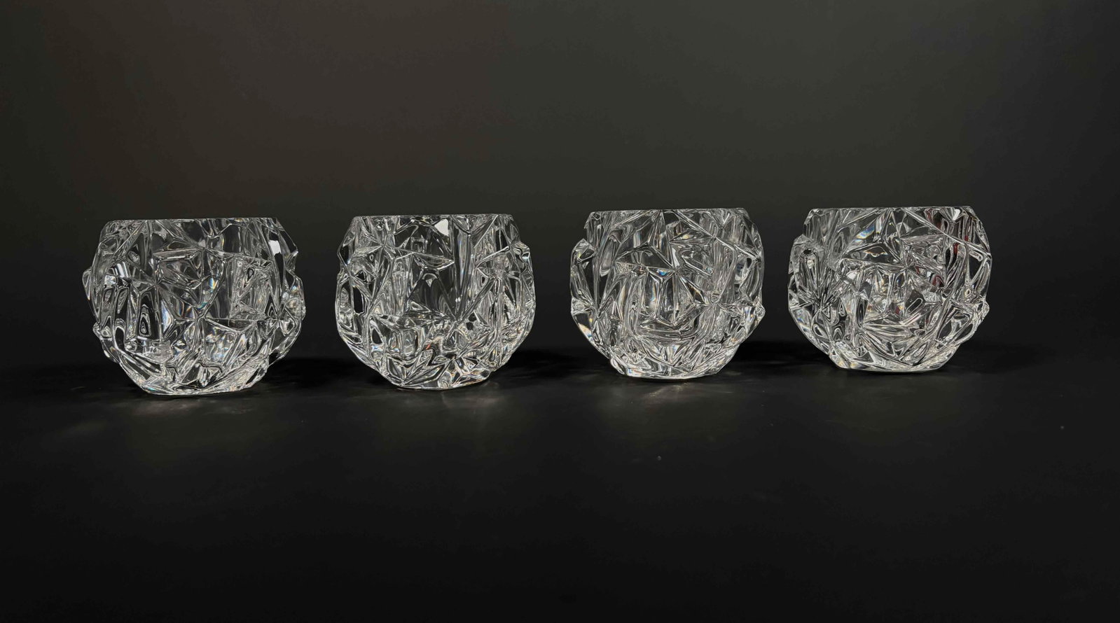 4 Crystal Votives by Tiffany and Co.: Four clear crystal votive candle holders by Tiffany and Co. Rock cut crystal. Tiffany and Co. hallmark is present on a clear, polished base. Excellent condition. No chips, scratches, or cracks. Please