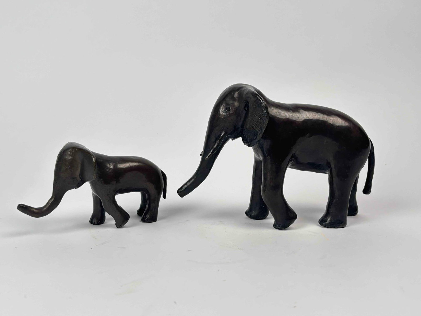 Bronze Sculpture of Two Elephants, Signed on Belly: A bronze sculpture featuring two elephants of varying sizes, signed on the belly of the larger elephant as pictured. Dimensions and weight are unspecified. The sculpture reflects signs of wear consist
