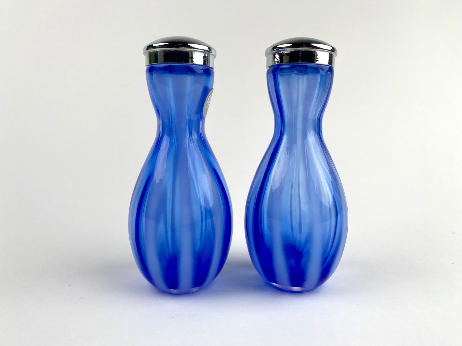 Fenton Blue Opaline 95th Anniversary Salt and Pepper Shakers: A pair of Fenton Art Glass salt and pepper shakers in cobalt blue with a striped pattern. Each shaker is topped with a polished silver-tone metal cap and features the Fenton marking, celebrating 95 ye