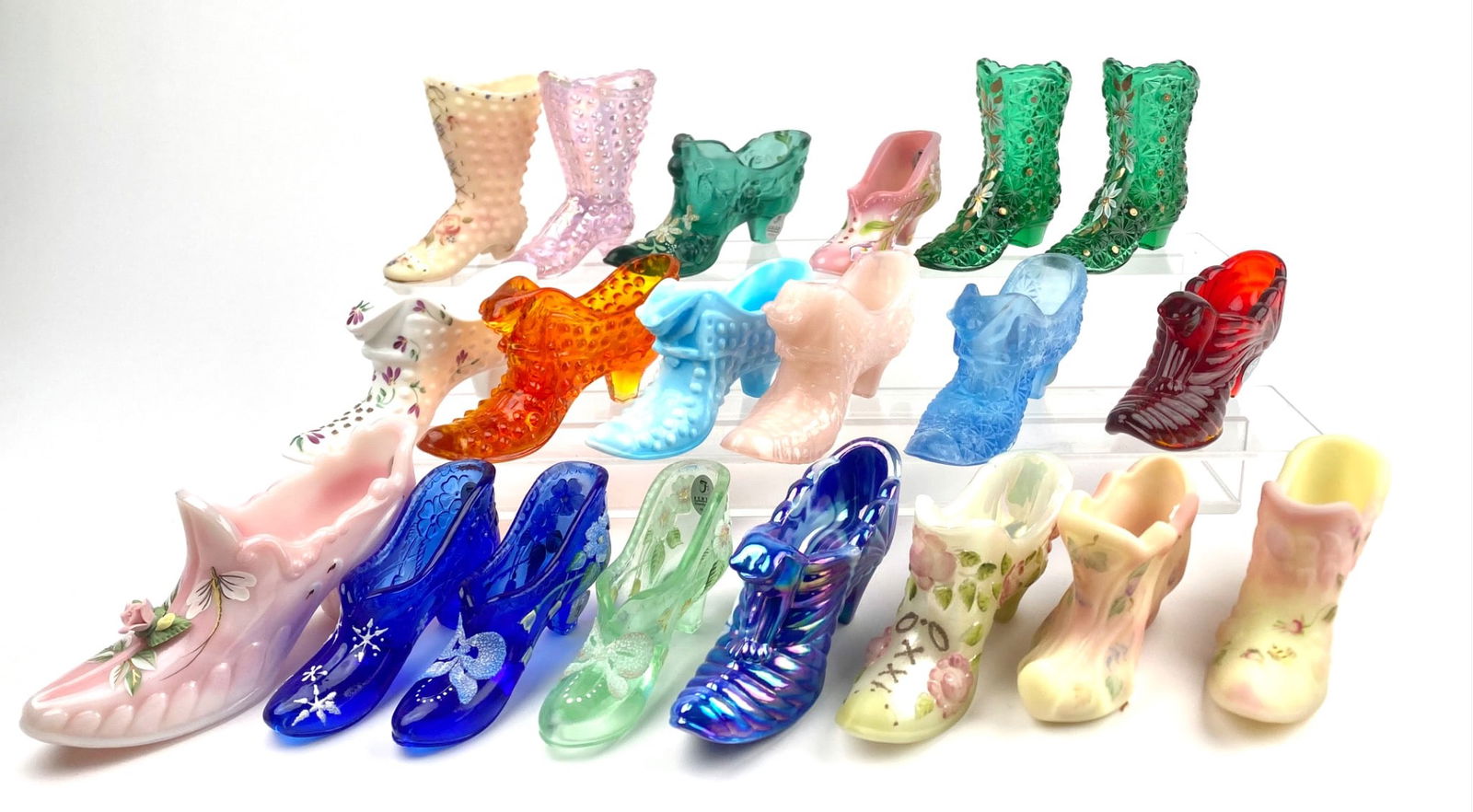 Lot of 20 Fenton Glass Shoes and Boots: Collection of intricately detailed miniature shoes and boots made of glass, porcelain, and other materials. Includes various styles such as hobnail boots, hand-painted floral shoes, and iridescent des