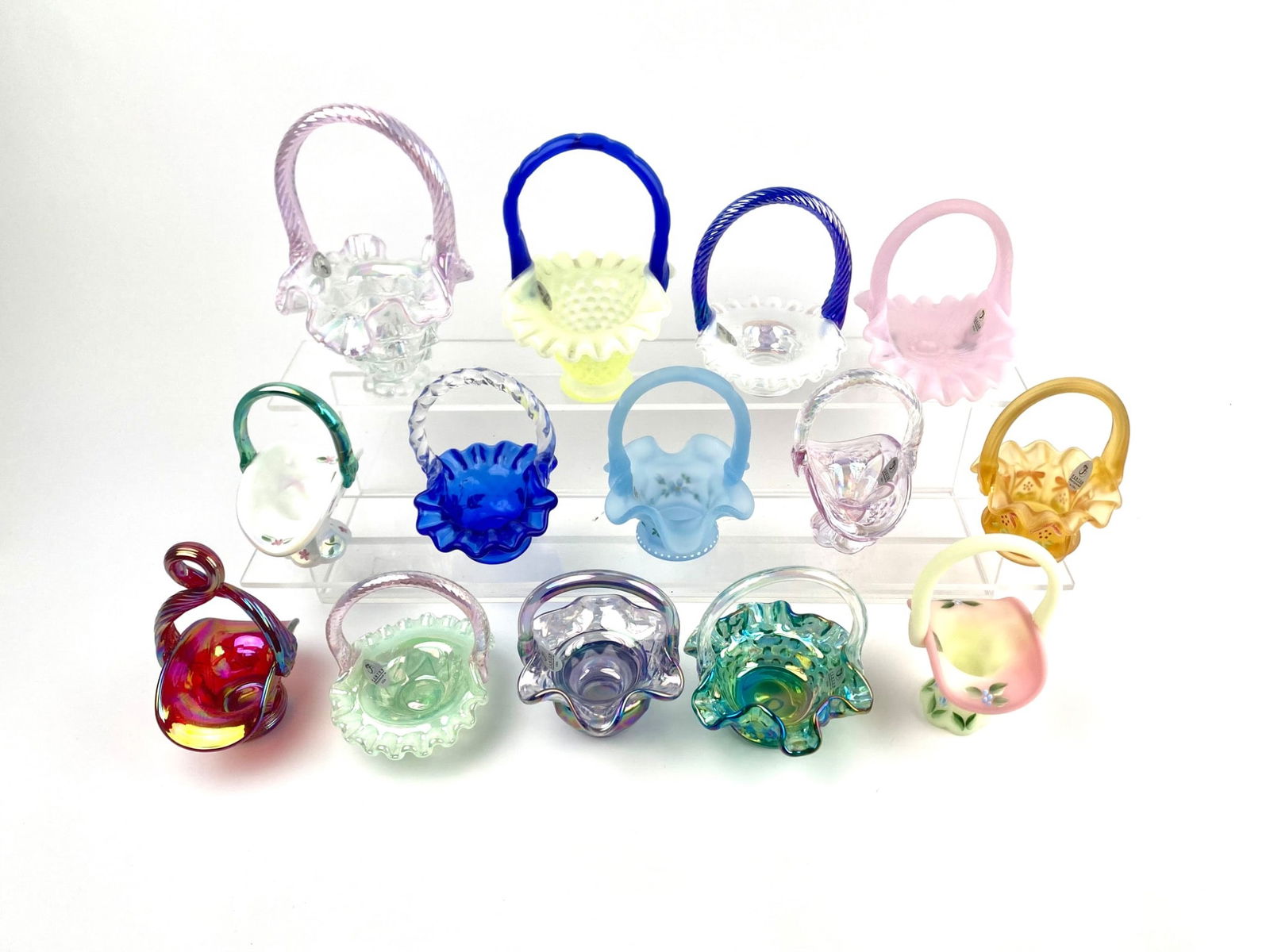 Collection of Miniature Fenton Glass Baskets: Group of 14 miniature art glass decorative baskets in various translucent and opaque colors. Includes different designs, finishing details, and patterns such as floral motifs, iridescent shades, and f