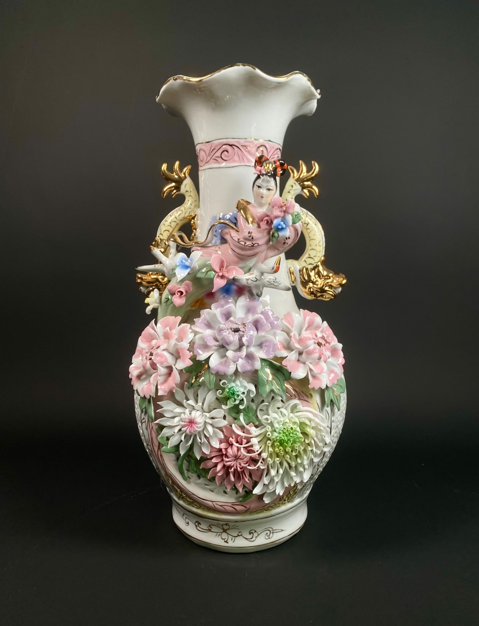 Hand-Painted Porcelain Vase Featuring Three Dimensional Floral Motif: A detailed hand-painted porcelain vase featuring a three dimensional floral motif, a central figure of a woman with delicate embellishments, and gilded dragons as side handles. The piece displays an i