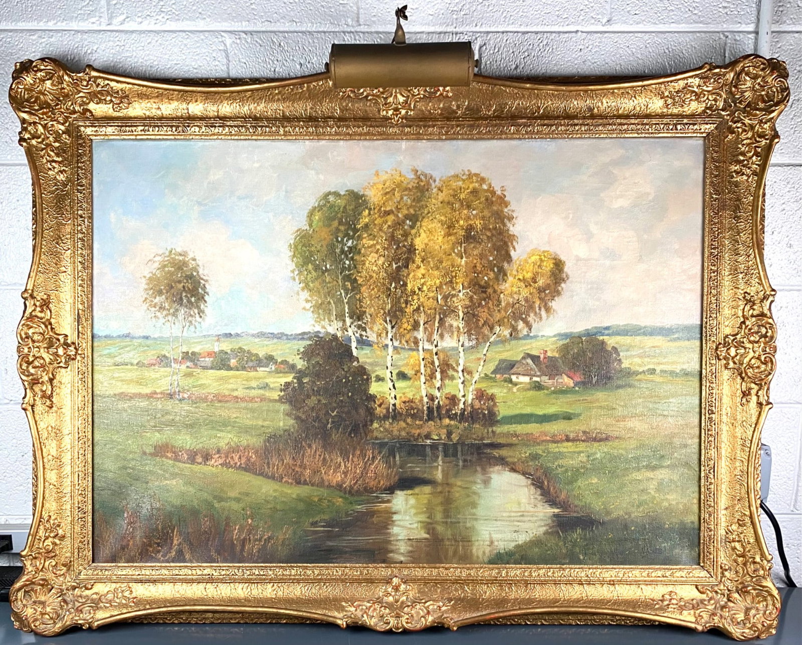 Oil Painting on Canvas by R. Krotter in Frame with Light: Oil painting on canvas by artist P. Kunter, depicting an idyllic rural setting with birch trees, a creek, and distant village structures, signed lower right. The artwork is housed in an elaborate gilt