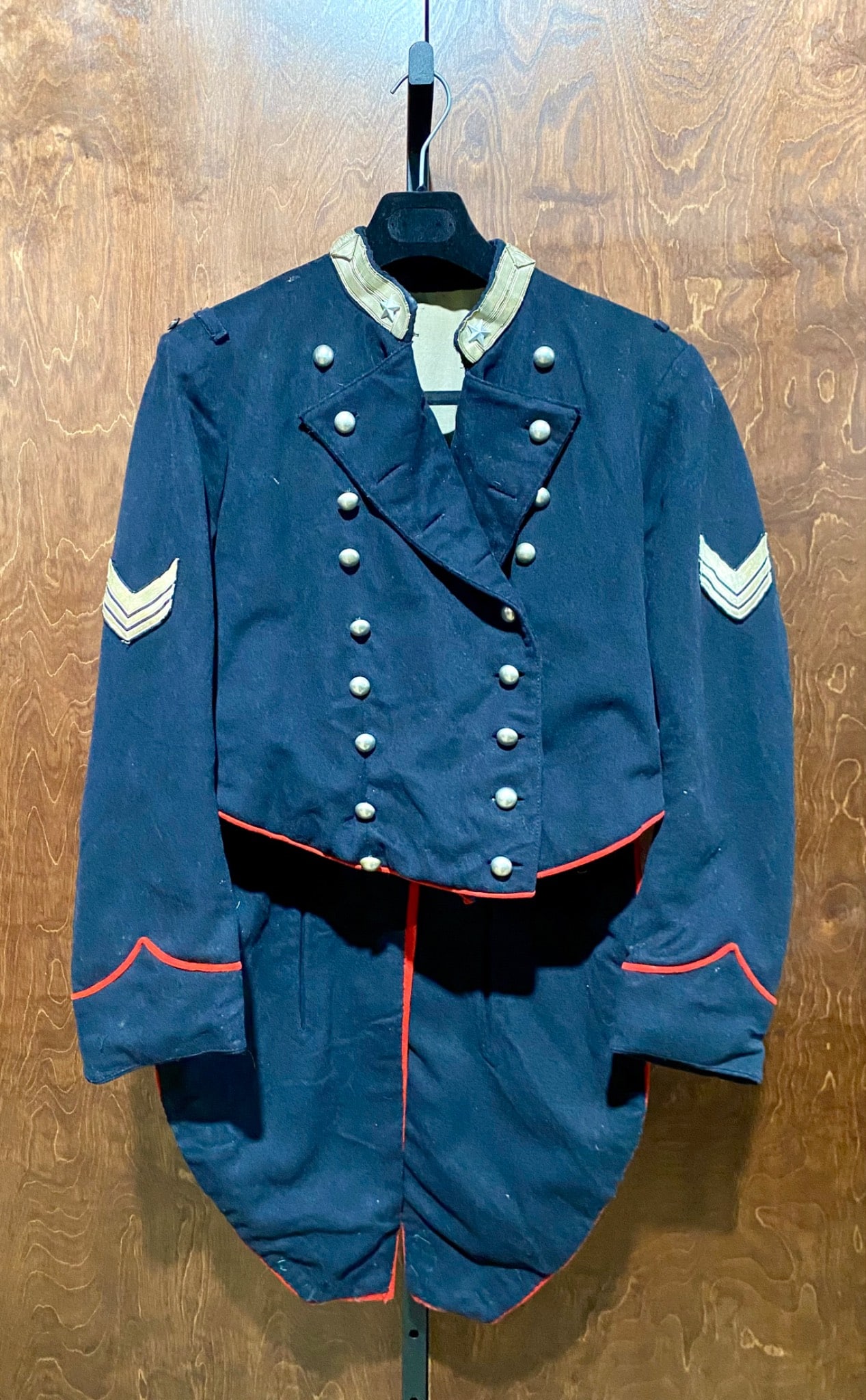 19th Century Military Tailcoat with Red Accents and Sergeant Stripes: 19th-century military tailcoat featuring dark blue wool with red accents along the cuffs, back, and hem. Double-breasted design with silver-tone buttons and a standing collar adorned with silver stars