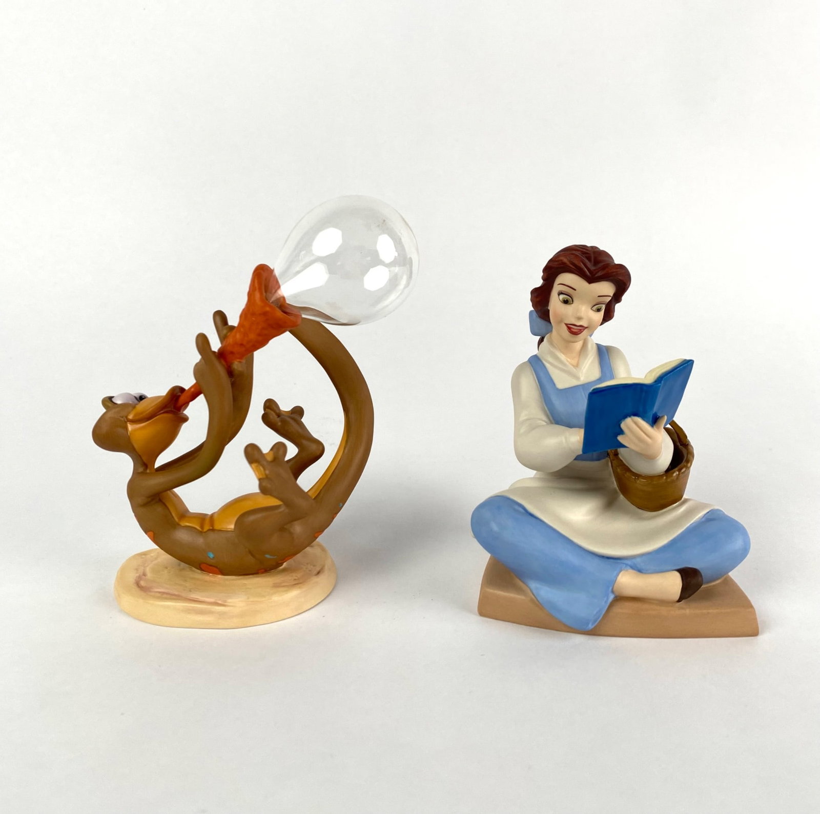 Two Disney Classic Collectibles: Belle and Newt: Two Disney collectible figurines. The first depicts Belle from Beauty and the Beast seated with a book, labeled on the base as Bookish Beauty Belle, 2005 Walt Disney Collectors Society Membership Scul