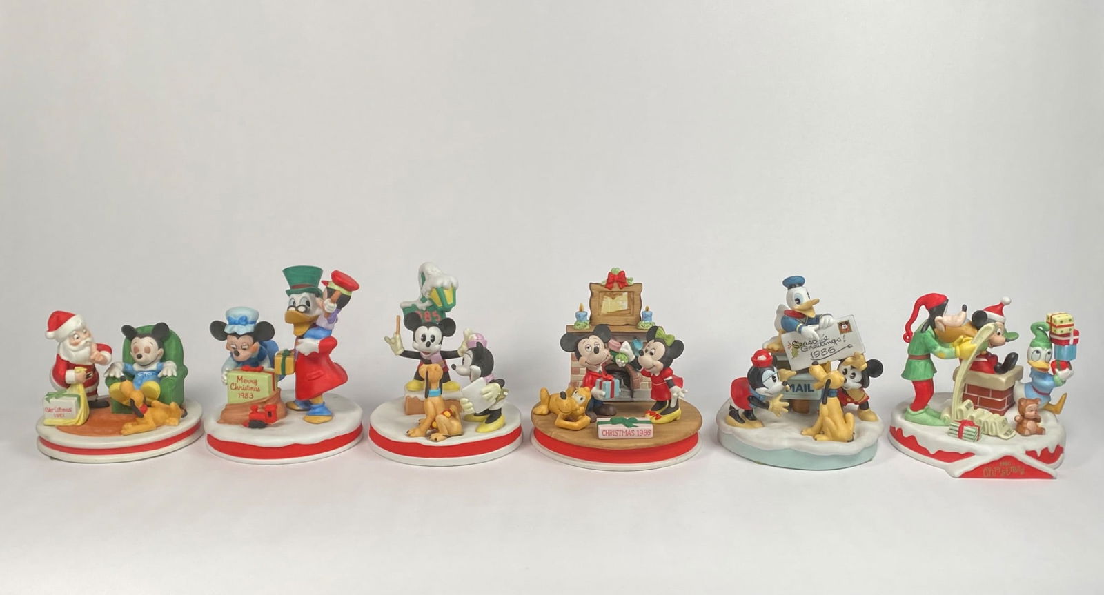 Set of Six Disney Christmas Figurines (1981 to 1990): A collection of six Disney Christmas figurines featuring classic characters such as Mickey Mouse, Minnie Mouse, Donald Duck, Goofy, and others. Each piece is from the Walt Disney Classic Collection an