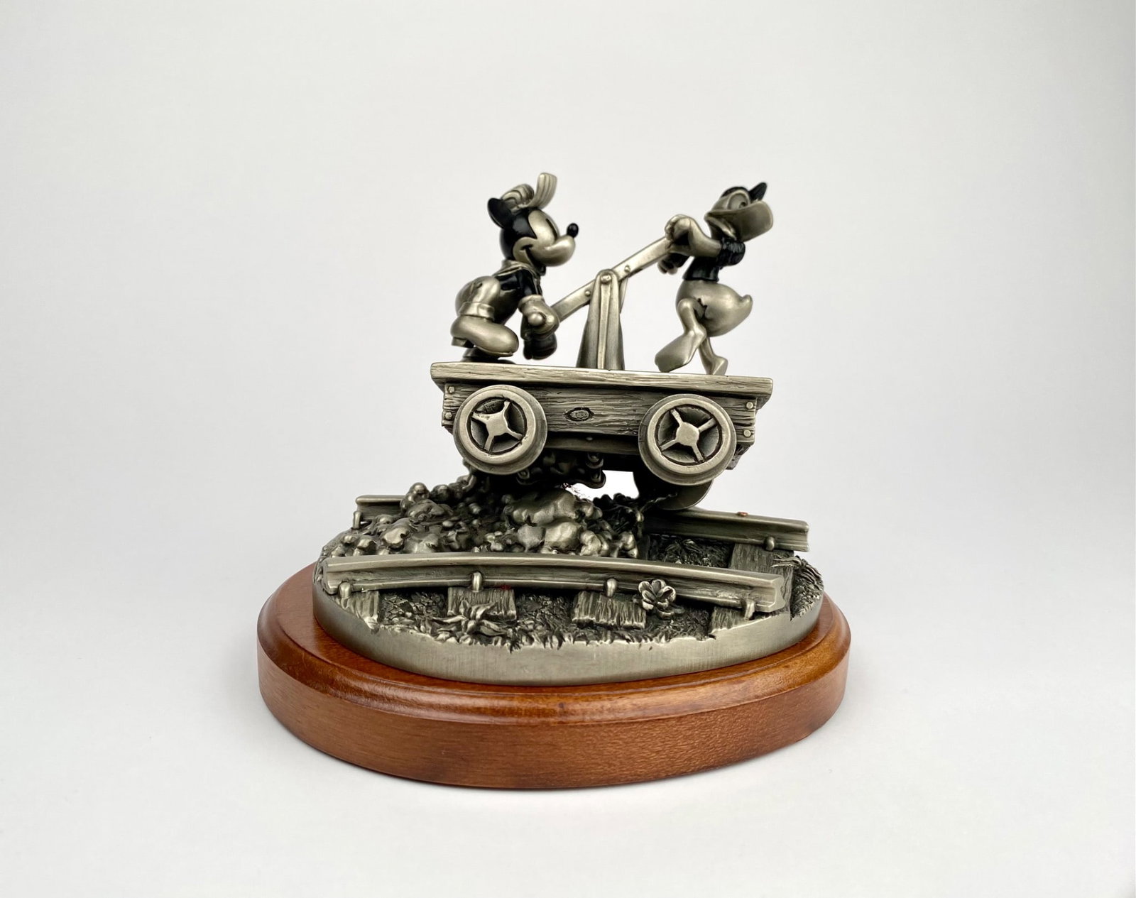 Chilmark Disney Sculpture Featuring Mickey and Donald (Original Box): Chilmark Fine Pewter sculpture featuring Mickey Mouse and Donald Duck on a handcar. This detailed piece is mounted on a polished wooden base and includes markings for Disney and Chilmark. The sculptur