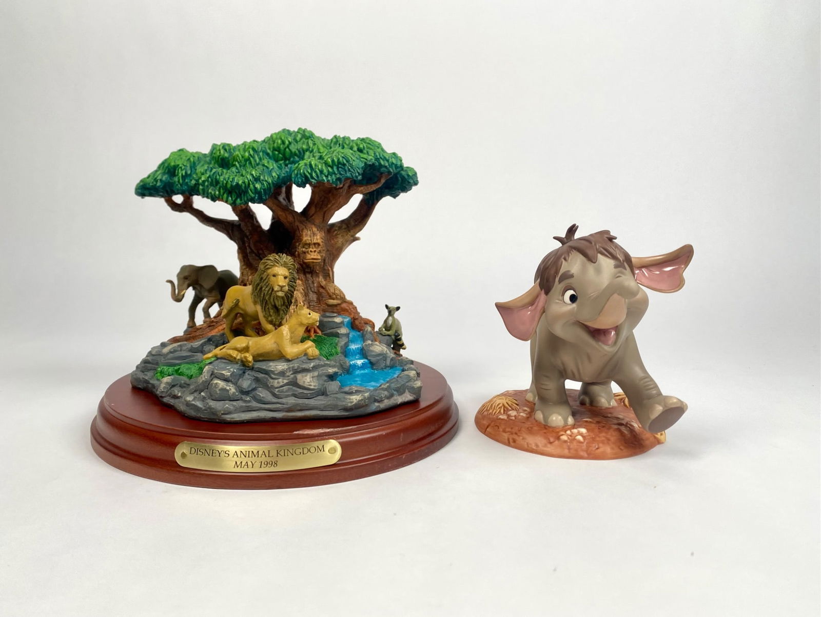 Disneys Animal Kingdom May 1998 Diorama and Jungle Book Figurine: Collection includes a diorama from Disney Animal Kingdom, dated May 1998, featuring a lion and lioness under a tree alongside other animals, on a detached wooden base with an engraved plaque. Accompan