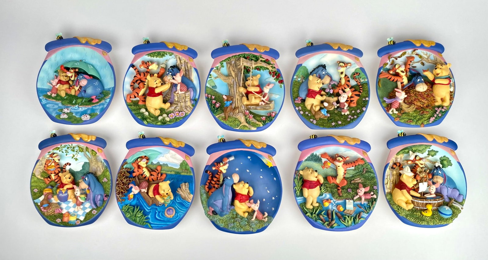 Set of 10 Winnie the Pooh Hanging Porcelain Scenes by Schmid: Set of 10 collectible porcelain hanging decorations featuring Winnie the Pooh scenes. Made by Schmid, each piece depicts a unique moment with Pooh and friends, designed as honey jar shaped ornaments w