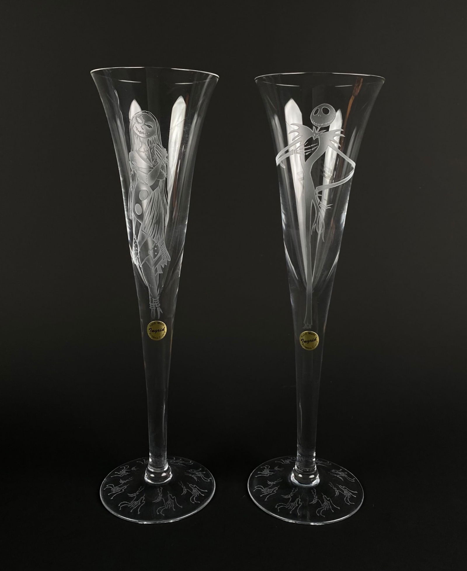 Set of Ingrid Disney Bohemia Crystal The Nightmare Before Christmas: Set of two etched Crystal glass flutes featuring characters Jack Skellington and Sally from Disneys The Nightmare Before Christmas. Both glasses have intricate engravings, including designs at the bas