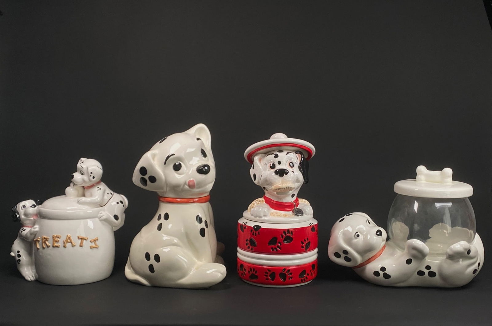 Set of Disney 101 Dalmatians Ceramic Cookie Jars: Set of Dalmatian themed ceramic containers, including four pieces: a treat jar with two puppies on the lid, a sitting Dalmatian dog cookie jar, a reclining Dalmatian glass jar with a bone lid, and a c
