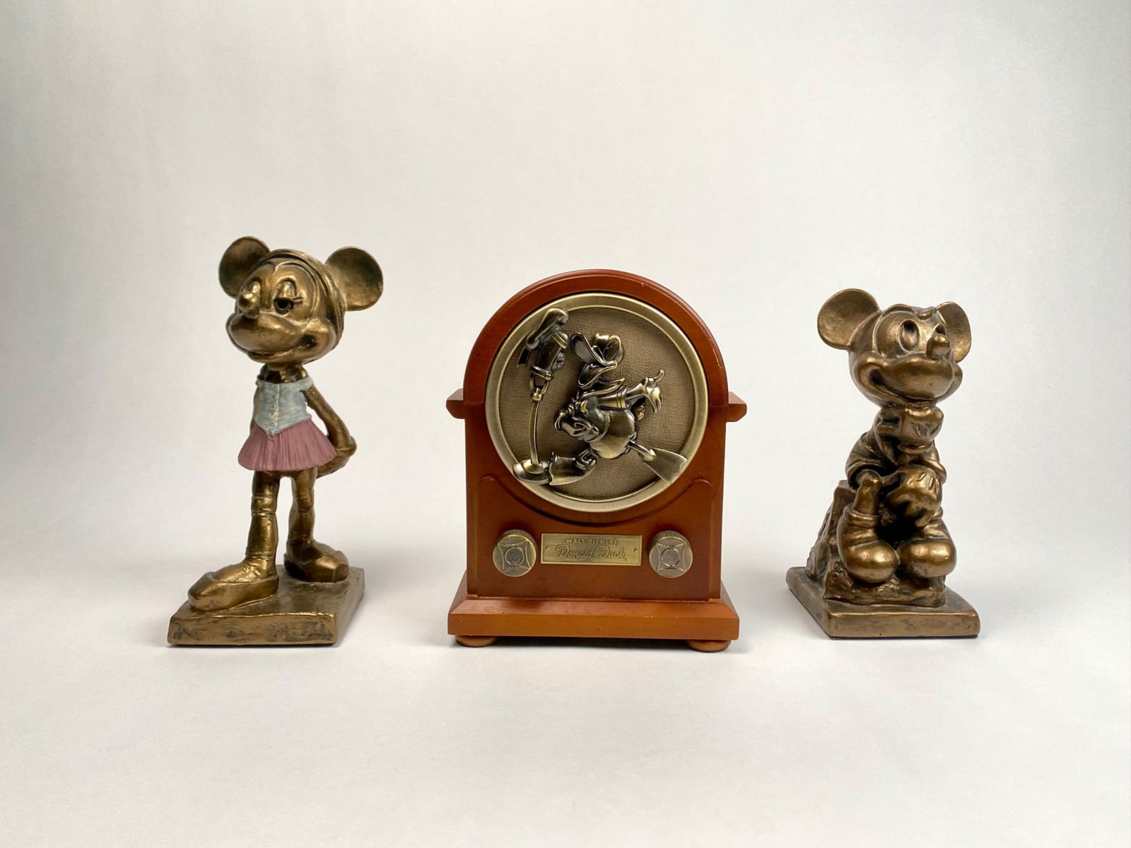 Set of Three Disney Figures: Set of three Disney collectibles, featuring two gold tone resin figures of Mickey and Minnie Mouse, each marked Disney at the base, and a 70th Anniversary Donald Duck radio shaped collectible made in