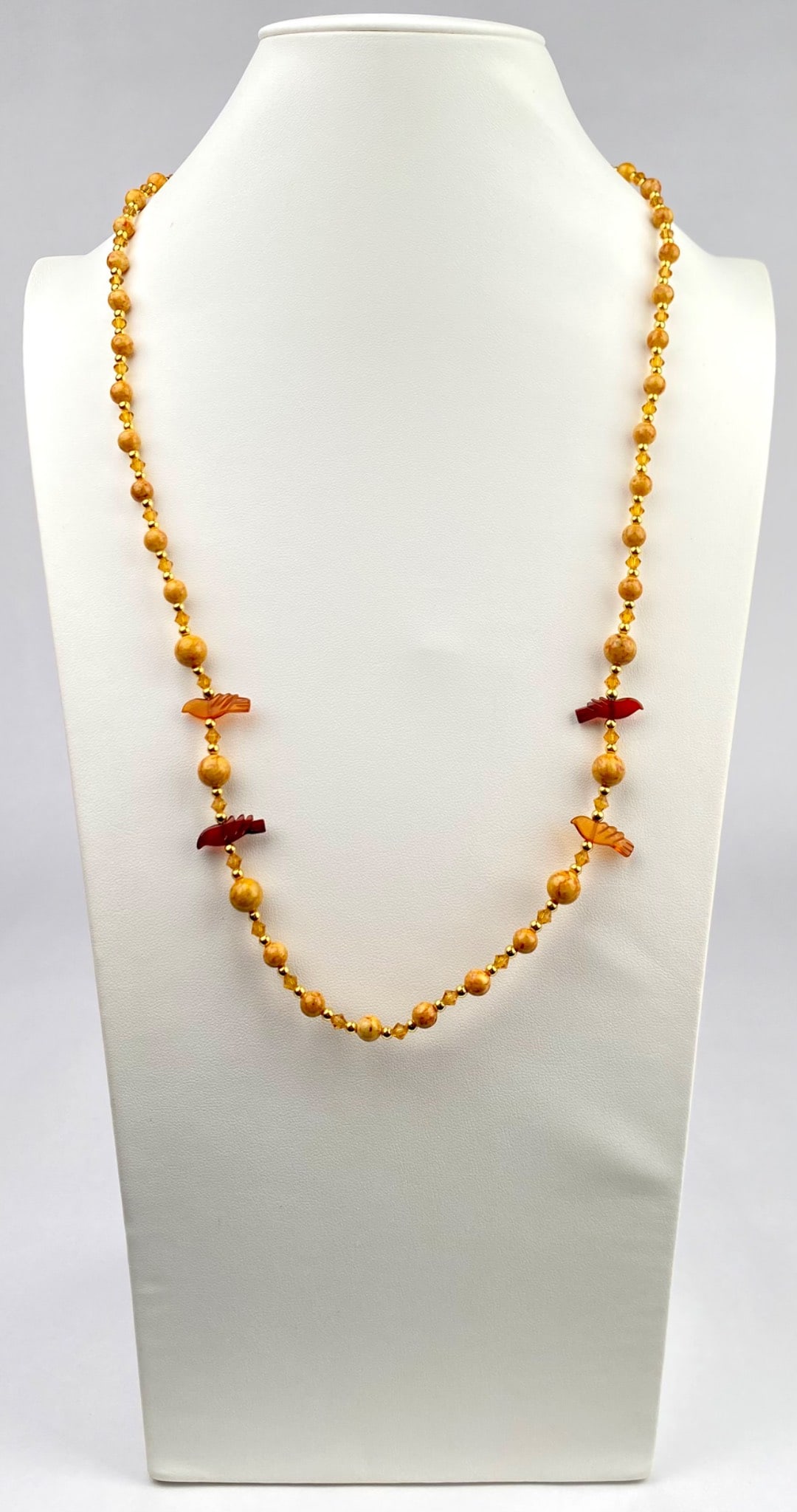 Vintage Beaded Necklace with Amber Bird Accents: Yellow beaded necklace featuring polished round beads alternating with smaller gold tone beads and faceted elements. The necklace is accented by bird shaped beads in a deep amber hue. Secured with an