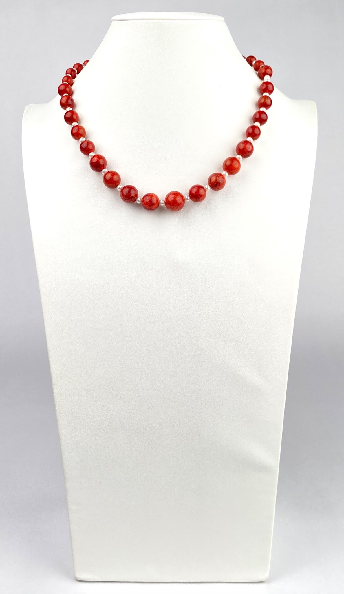 Red Coral and Pearl Beaded Necklace With Sterling Silver Clasp: Red coral beads and simulated pearls are strung together on this elegant necklace, featuring a silver clasp marked 925. The round beads are alternated with faux pearls for a dynamic design. Necklace i