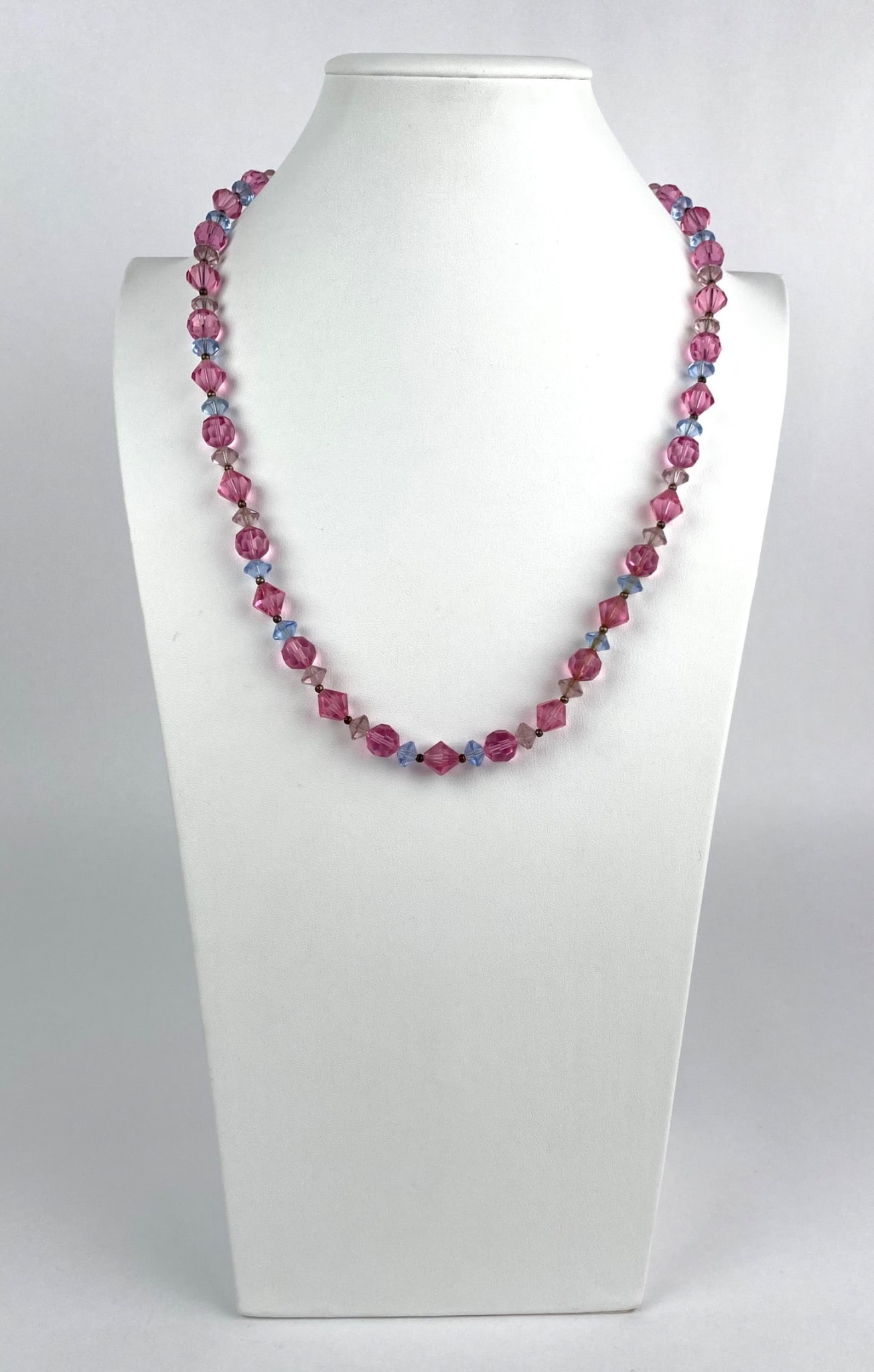 Vintage Pink and Blue Crystal Necklace With Filigree Clasp: Pink and blue beaded necklace featuring faceted beads of varying shapes and sizes strung together, secured with a decorative filigree box clasp adorned with a pink bead at the center. The necklace dis