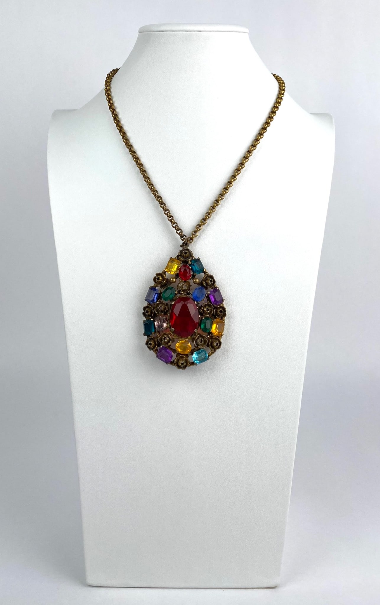 Coro Gold Tone Necklace with Multicolored Rhinestone Pendant: Coro gold tone chain necklace featuring a large teardrop-shaped pendant adorned with multicolored rhinestones, including red, purple, yellow, green, and blue accents. The back of the pendant is marked