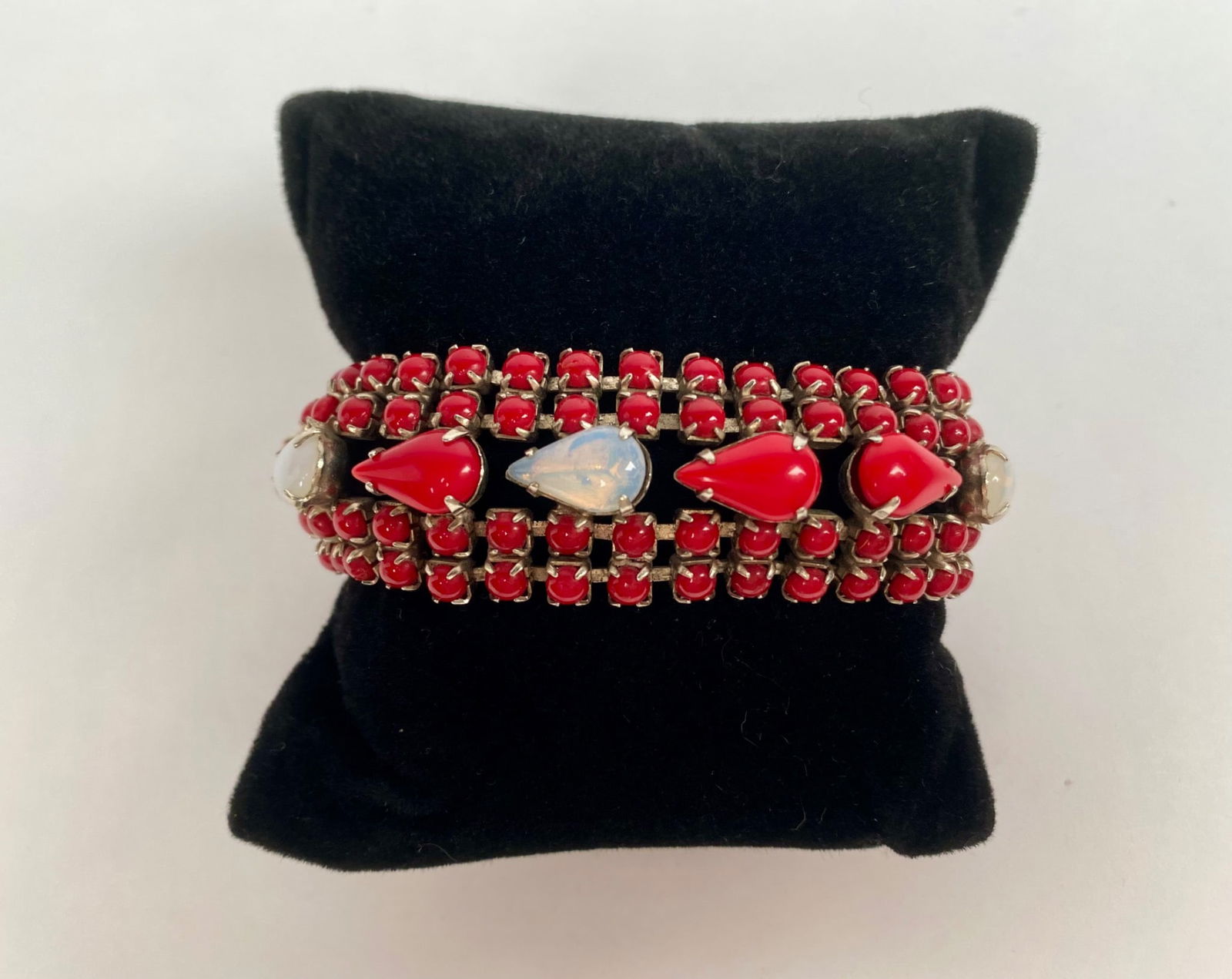 Vintage Red and White Teardrop Rhinestone Bracelet: A bracelet featuring red and opaline white teardrop shaped rhinestones in a gold tone metal frame. The bracelet is composed of a uniform pattern of small red stones, creating a bold and elegant design