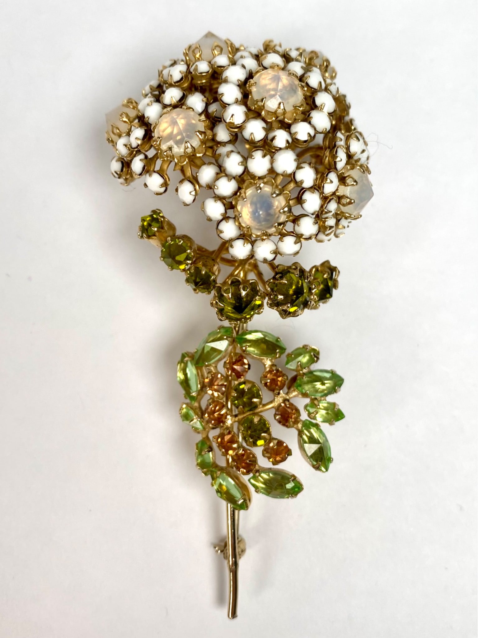 Signed Schreiner New York Floral Bouquet Brooch: A Schreiner New York floral brooch featuring opalescent and white enamel beads arranged in a clustered flower design, accented with green and amber toned rhinestones. The piece is set in a gold tone m