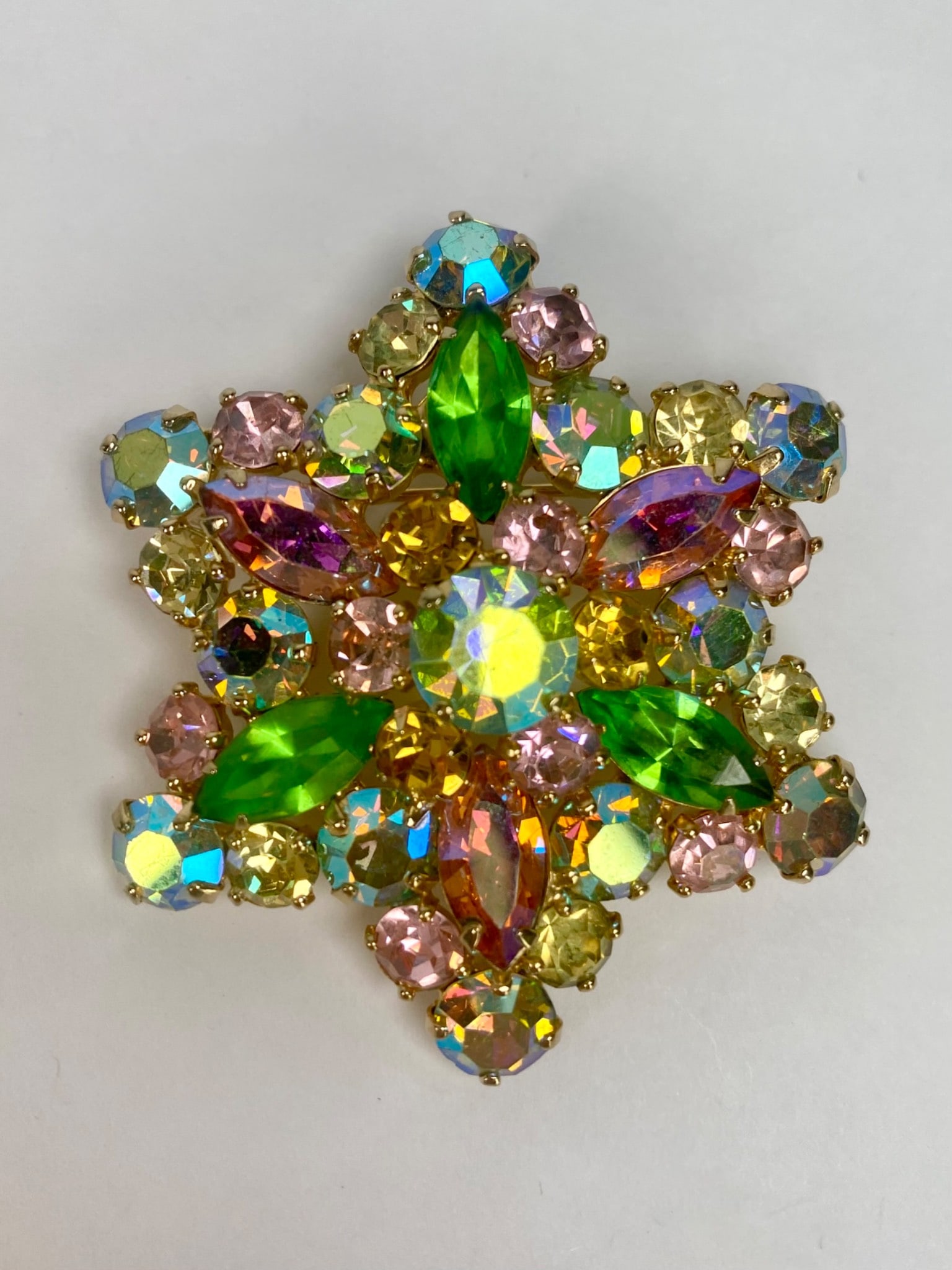 Weiss Multicolor Rhinestone Starburst Brooch: Weiss star shaped brooch featuring vibrant multicolor rhinestones including green marquise, yellow, pink, and iridescent stones. Stone shape varies among round and marquise cut creating a dimensional 