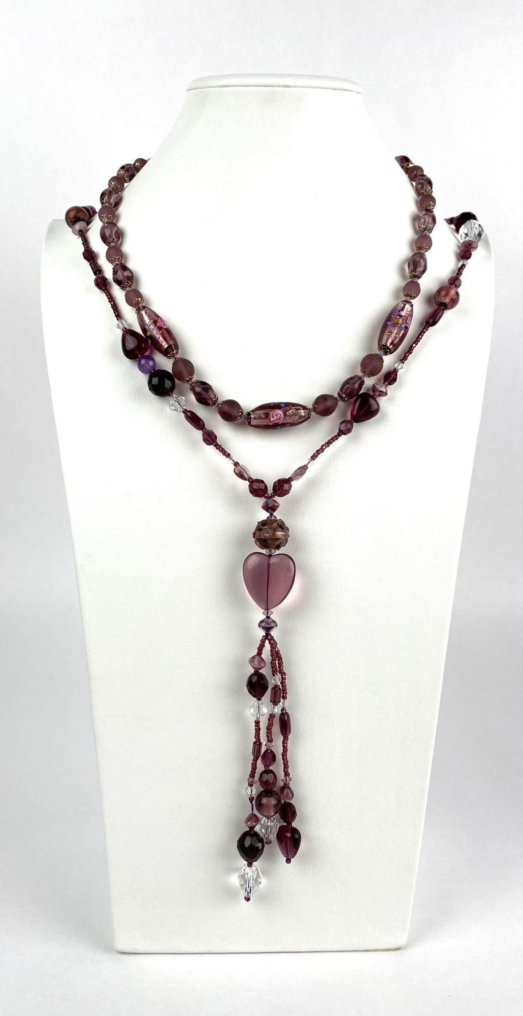 Sunya Currie Venetian Glass Jewelry Collection Two Necklaces: Two necklaces from the Sunya Currie Venetian Glass Jewelry Collection, handcrafted in workshops of Venice, Italy. Features an assortment of purple and clear glass beads, including a heart shaped bead 