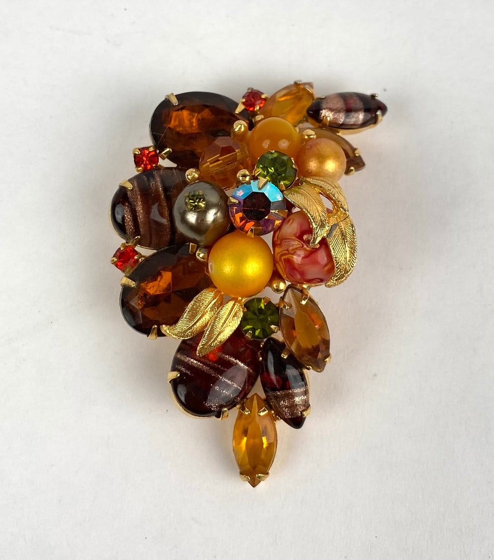 Gold Tone Brooch with Multicolored Beads and Rhinestones: Gold tone brooch featuring an abstract arrangement of multicolored beads, rhinestones, and marbled embellishments. The brooch is adorned with gold painted details and leaf like accents, with a secure 