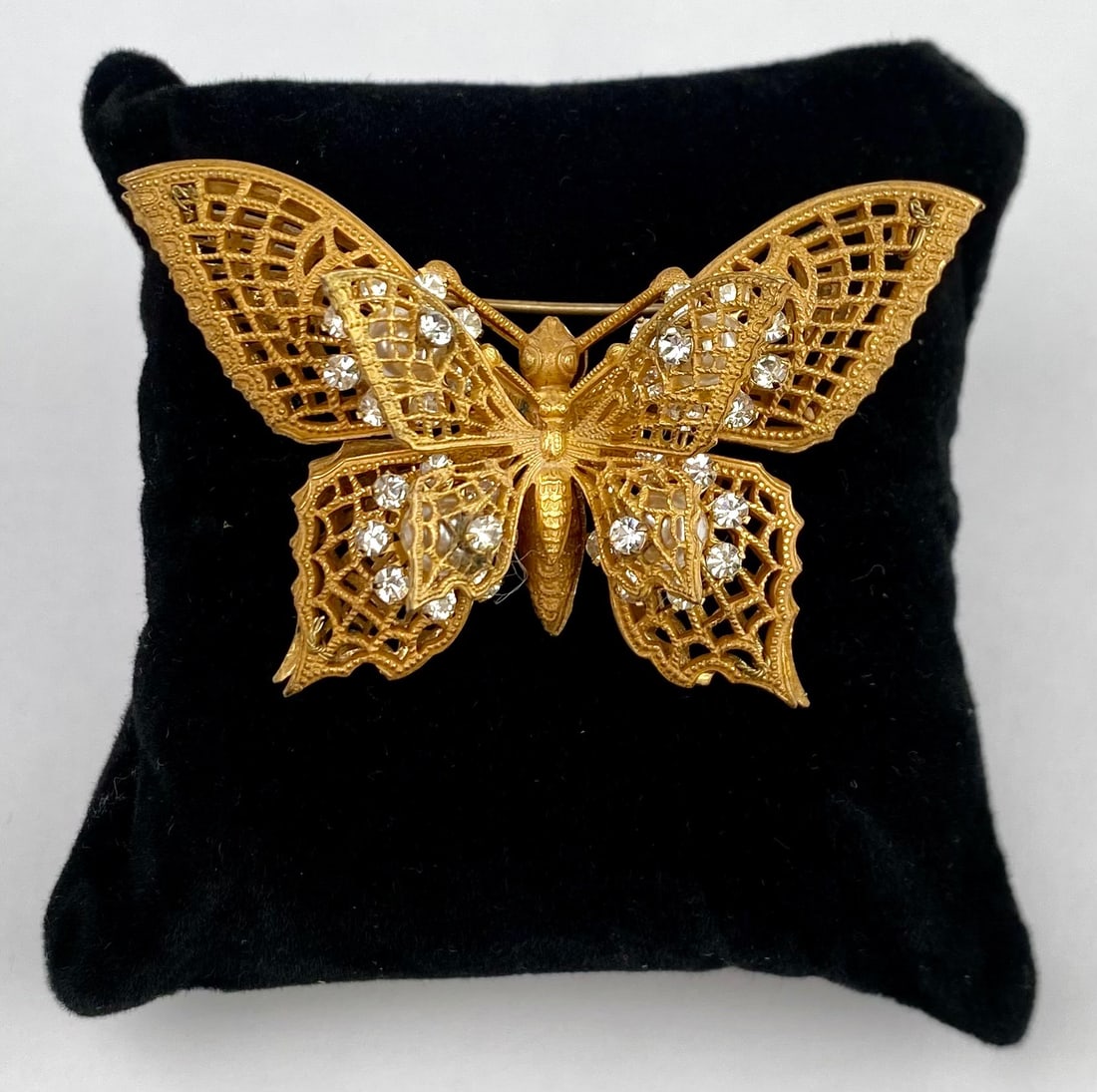 Miriam Haskell Butterfly Brooch with Rhinestones: Miriam Haskell gold tone butterfly brooch featuring a lattice style wing design accented with sparkling rhinestones and faux pearls. The piece showcases the makers plaque on the reverse, confirming it