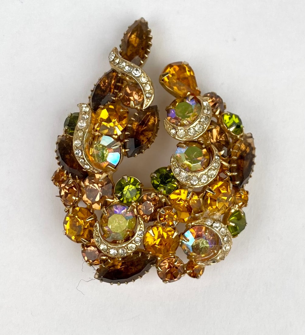 Multicolor Rhinestone Brooch with Gold Tone Backing: Multicolor rhinestone brooch featuring a vibrant arrangement of green, amber, brown, yellow, and iridescent stones in various cuts. The brooch is set in a gold tone metal backing with a secure pin clo