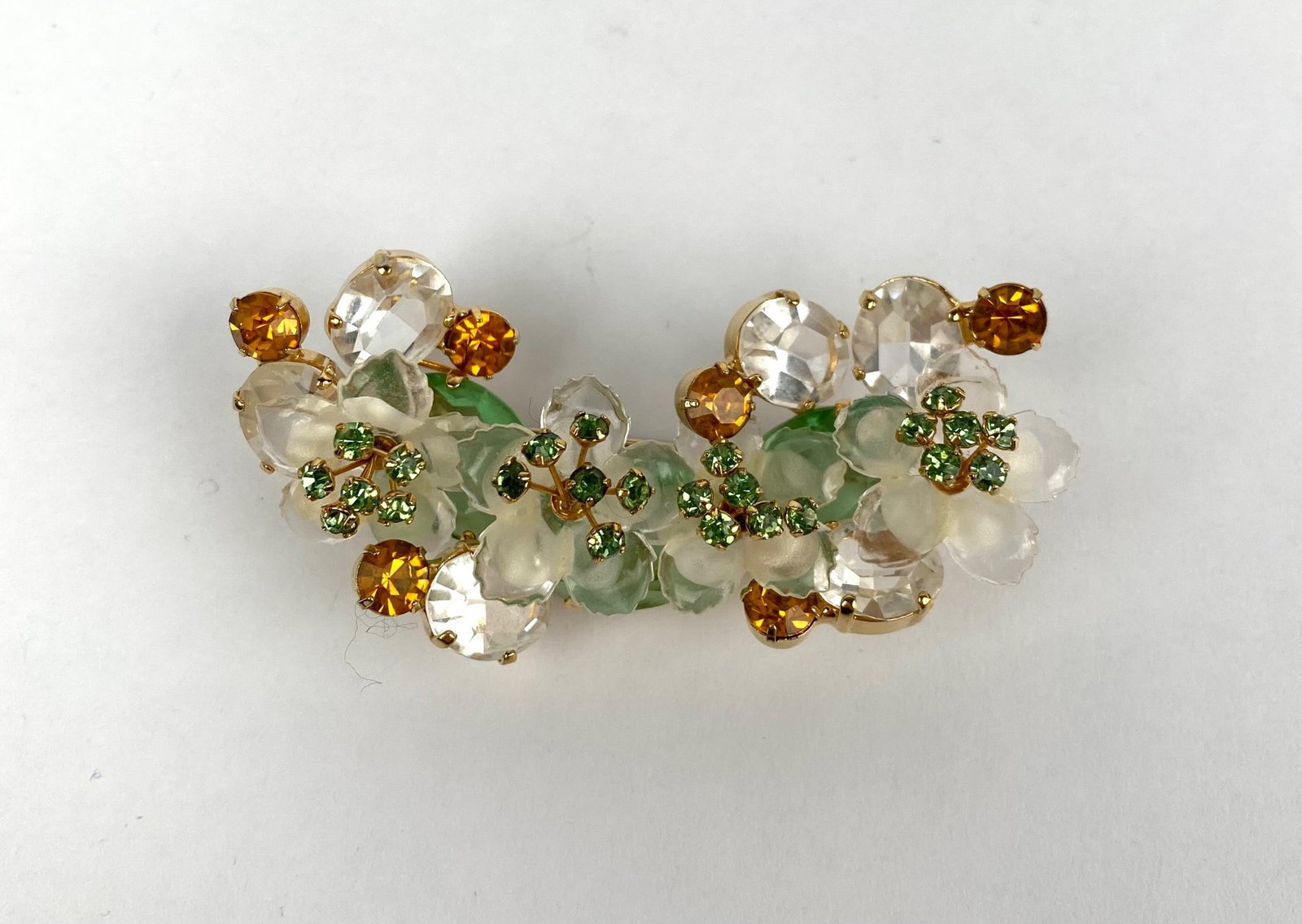 Vendome 1970s Gold Tone Floral Brooch: Vendome gold-tone floral brooch featuring white and green enameled floral details accented with clear and amber toned faceted crystals. The back of the brooch is marked Vendome. Pin mechanism is funct